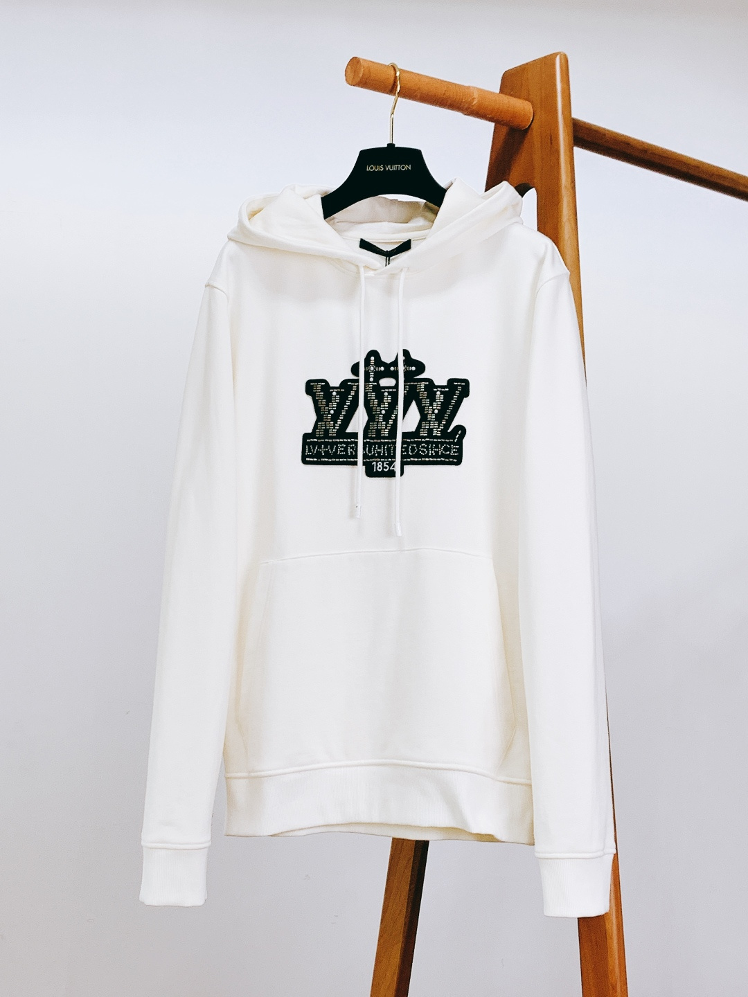 NO:595695,LouisVuitton Louis Vuitton's 2025FW new autumn and winter collection-level hooded sweatshirt. The front uses black metal beading + rhinestone splicing technology, integrating the classic brand letter logo and the brand's founding year '1854' into a three-dimensional badge shape. The beading is densely arranged and has a strong luster, and is embellished with rhinestones. It presents a rich sense of sophistication under different lights, and is both recognizable and artistic.  The drawstring uses a thick woven rope strap of the same color, with a brand-engraved hanging clock at the end, combining the brand logo with elegant elements, and highlighting the luxury tone in the details; It is made of heavy cotton blended fabric, which is soft and skin-friendly and stiff and not easily deformed. The micro-velvet design inside improves wearing comfort; the loose shoulder design is suitable for various wearing scenarios (daily casual / casual style), and the ribbed edges on the hem and cuffs not only ensure a good fit, but also enhance the neatness of the silhouette.  This sweatshirt breaks the stereotype of 'luxury = formal' and integrates brand logo genes, high-luxury craftsmanship and casual attributes. It is a 'low-key and noble' collection-level item for daily wear. ……………………………………………… SizeS-XL,,louis vuitton,louis vuitton,hoodie,sweatshirts,hats,alexander wang19860909LouisVuitton 路易威登 2025FW秋冬新品 典藏级连帽卫衣.正面采用黑底金属钉珠+水钻拼接工艺,将经典品牌字母标识、品牌创立年份“1854”融入立体徽章造型,钉珠排列细密且光泽感强,水钻点缀其间,在不同光线下呈现层次丰富的精致感,兼具辨识度与艺术感. 抽绳采用同色系粗织绳带,末端搭配品牌刻字吊钟,将品牌标识与优雅元素结合,细节处彰显奢品调性； 采用重磅棉混纺面料,触感柔软亲肤且挺括不易变形,内里微绒设计提升穿着舒适度；宽松落肩版型,适配多元穿搭场景（日常休闲/轻熟风皆可）,下摆与袖口的罗纹收边,既保证贴合度,又强化了廓形的利落感. 这款卫衣打破了“奢品=正式”的刻板印象,将品牌标识基因、高奢工艺与休闲属性融合,是日常穿搭中“低调显贵”的典藏级单品. …………………………………………………… SizeS-XL,,louis vuitton,louis vuitton,hoodie,sweatshirts,hats,alexander wang,Men's clothing