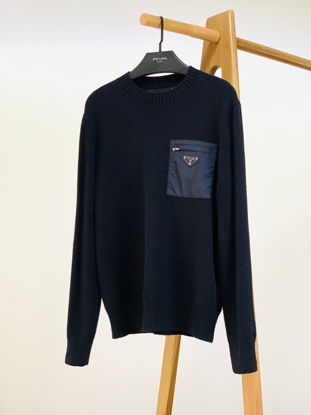 NO:691305,Prada 2025FW new autumn and winter nylon pocket sweater. The soft and waxy knitted base has a delicate texture, and the spliced nylon patch on the chest is the finishing touch - the softness of matte knitting meets the light and tough texture of nylon, combining the neatness of sports style and the laziness of knitting.  The classic triangular hardware logo on the patch is the 'invisible seal' of brand recognition. The small area of metallic luster is not ostentatious, but the brand's style can be recognized at a glance; even the ribbed edges of the collar and cuffs are made carefully and neatly, and there is sophistication hidden in the looseness. The round neck + slightly loose tailoring is not flattering on the figure, and it is casual and everyday to wear with jeans, and it can be worn with a layered suit to look 'sophisticated and elegant'; the black and white/navy blue two-color suit different styles, and can be used for commuting and leisure.  Size 46, length 68, chest 100, shoulder width 43, sleeve length 60, size 48, length 70, chest 104, shoulder width 44.5, sleeve length 61, size 50, length 72, chest 108, shoulder width 46, sleeve length 62, size 52, length 74, chest 112, shoulder width 47.5, sleeve length 63…………………………………………………………………  Size46-52,,prada,prada,jeans,business suit,19860909Prada 普拉达 2025FW秋冬新品 尼龙口袋针织衫.软糯针织基底带着细腻肌理,胸前拼接的尼龙贴布是点睛之笔——哑光针织的柔,撞上尼龙的轻韧质感,把运动风的利落和针织的慵懒揉得刚好. 贴布上经典三角标五金徽标是品牌辨识度的“隐形印章”,小面积金属光泽既不张扬,又能一眼认出品牌的格调；连领口、袖口的罗纹收边都做得细密工整,松弛中藏着精致. 圆领+微宽松剪裁不挑身材,搭牛仔裤是随性日常,叠穿西装又能穿出“轻熟贵气”；黑白/藏蓝双色适配不同风格,通勤、休闲都能搭. 46码衣长68 胸围100 肩宽43 袖长60 48码衣长70 胸围104 肩宽44.5 袖长61 50码衣长72 胸围108 肩宽46 袖长62 52码衣长74 胸围112 肩宽47.5 袖长63 …………………………………………………… Size46-52,,prada,prada,jeans,business suit,,Men's clothing