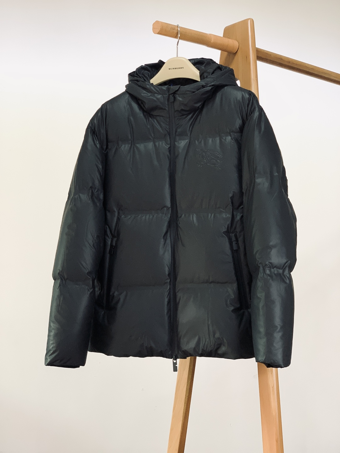 NO:691214,Burberry 2025FW new autumn and winter hooded leather down jacket. The body is made of textured leather fabric, which is delicate to the touch, crisp and stylish; it is filled with 90 white duck down, which has excellent fluffiness and warmth, and can lock in temperature in cold winter without being bulky.  The brand's classic equestrian knight logo is embossed on the chest, and the embossed texture fully demonstrates the brand's recognition. It is unobtrusive but has a high-end aura. The all-black matte zipper is equipped with a customized metal puller, which opens and closes smoothly while echoing the style of the body. The elastic rib design of the cuffs fits the wrist to prevent wind and warmth; the waist is engraved with the brand  The character drawstring buckle allows you to freely adjust the silhouette, taking into account both practicality and design. The lining is made of iconic plaid fabric, which collides with the retro British style and modern down silhouette. The plaid details are exposed at the folds, and the sense of layering is instantly full. From the fabric selection to the turning and wiring, every aspect highlights the level of luxury craftsmanship.  ……………………………………………………………… SizeM-3XL,,burberry,burberry,jackets & coats,down jacket,hats,19860909Burberry 巴宝莉 2025FW秋冬新品 连帽皮羽绒外套.采用质感皮革面料打造衣身,触感细腻且挺括有型；内里填充90白鸭绒,蓬松度与保暖性双优,寒冬锁温不臃肿. 胸前压印品牌经典马术骑士徽标,浮雕质感尽显品牌辨识度,不张扬却自带高级气场.全黑哑光拉链搭配定制金属拉头,顺滑开合的同时与衣身风格呼应；袖口弹力罗纹设计,贴合腕部防风保暖；腰部配品牌刻字抽绳扣,可自由调节廓形,兼顾实用性与设计感.内衬采用标志性格纹面料,复古英伦风与现代羽绒廓形碰撞,翻折处露出格纹细节,层次感瞬间拉满.从面料选材到车工走线,每一处都彰显奢品工艺水准. …………………………………………………… SizeM-3XL,,burberry,burberry,jackets & coats,down jacket,hats,,Men's clothing