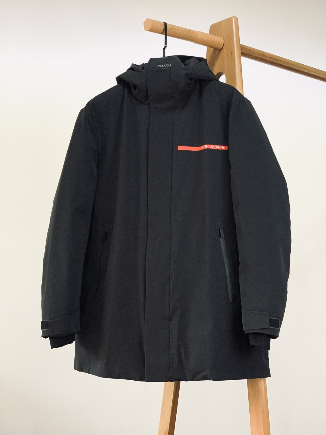 NO:691321,Prada's new 2025FW autumn and winter mid-length hooded down jacket. Made of three-layer waterproof fabric made of recycled polyester fiber, with graphene membrane technology, it is windproof, waterproof and breathable. It can cope with rain and snow without any pressure, and makes outdoor travel more secure.  The red rubber strip on the chest is embedded with the white brand letter logo; the cuffs are designed with Velcro adjustment, the tightness can be adjusted freely, and it fits the wrist effectively to prevent wind; the zippers are all engraved with the brand logo, opening and closing smoothly while improving the texture; the sides are breathable mesh design, balanced  Warmth and breathability prevent stuffiness. The drawstring buckle is made of the brand's classic rhombus rubber material, with clear engravings and a thick texture. The metal air eyes are paired with the drawstring to reinforce the details and make adjustments more convenient. Every piece of hardware shows luxury craftsmanship.  The mid-length silhouette modifies the body shape and covers the buttocks and thigh lines without weighing down the body; the hooded design fits the contours of the head, making it both fashionable and practical for daily commuting and outdoor leisure wear. ……………………………………………… SizeM-3XL,, prada, prada, down jacket, hats,19860909Prada 普拉达 2025FW秋冬新品 中长款连帽羽绒服.采用再生聚酯纤维打造的三层防水面料,搭配石墨烯膜技术,防风防水又透气,应对雨雪天气毫无压力,户外出行更安心. 胸前红色橡胶饰条嵌印白色品牌字母标识；袖口采用魔术贴调节设计,可自由调整松紧度,贴合腕部有效防风；拉链均刻印品牌标识,顺滑开合的同时提升质感；侧边透气网布设计,平衡保暖性与透气性,避免穿着闷热.抽绳扣采用品牌经典的菱格纹橡胶材质,刻字标识清晰,质感厚重；金属气眼与抽绳搭配,加固细节的同时,让调节更便捷,每一处五金都尽显奢品工艺. 中长款廓形修饰身形,不压个子还能遮盖臀部与大腿线条；连帽设计贴合头部轮廓,日常通勤、户外休闲穿都能兼顾时尚与实用. …………………………………………………… SizeM-3XL,,prada,prada,down jacket,hats,,Men's clothing