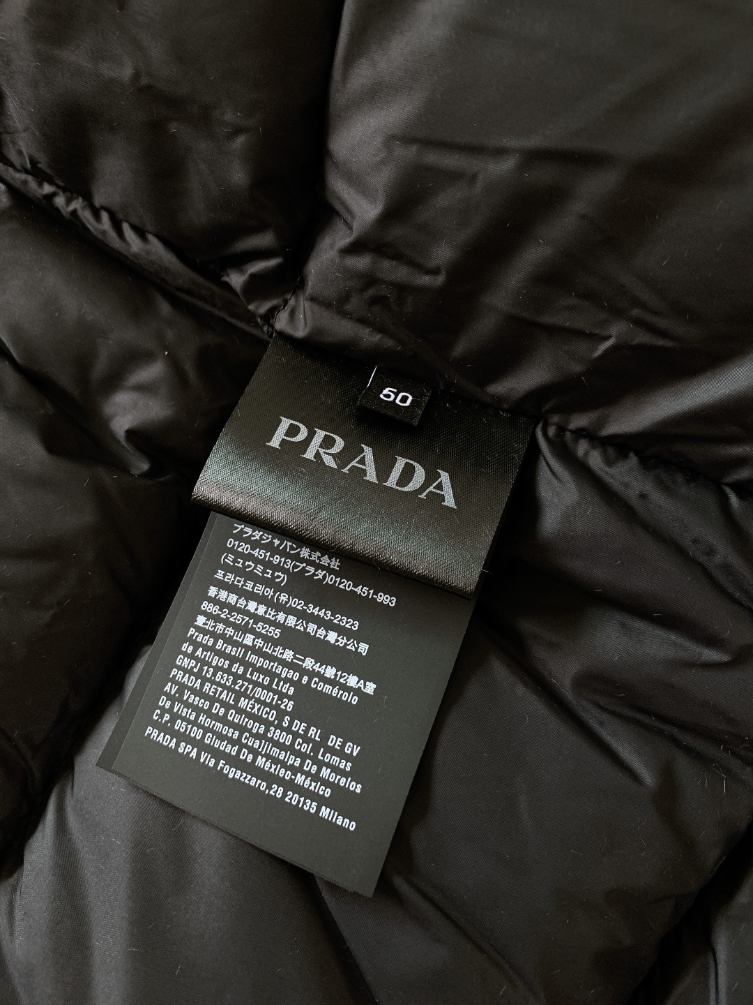 Prada 普拉达 2025FW秋冬新品中长款连帽羽绒服。采用100%再生聚酯纤维打造的三层防水面料，搭