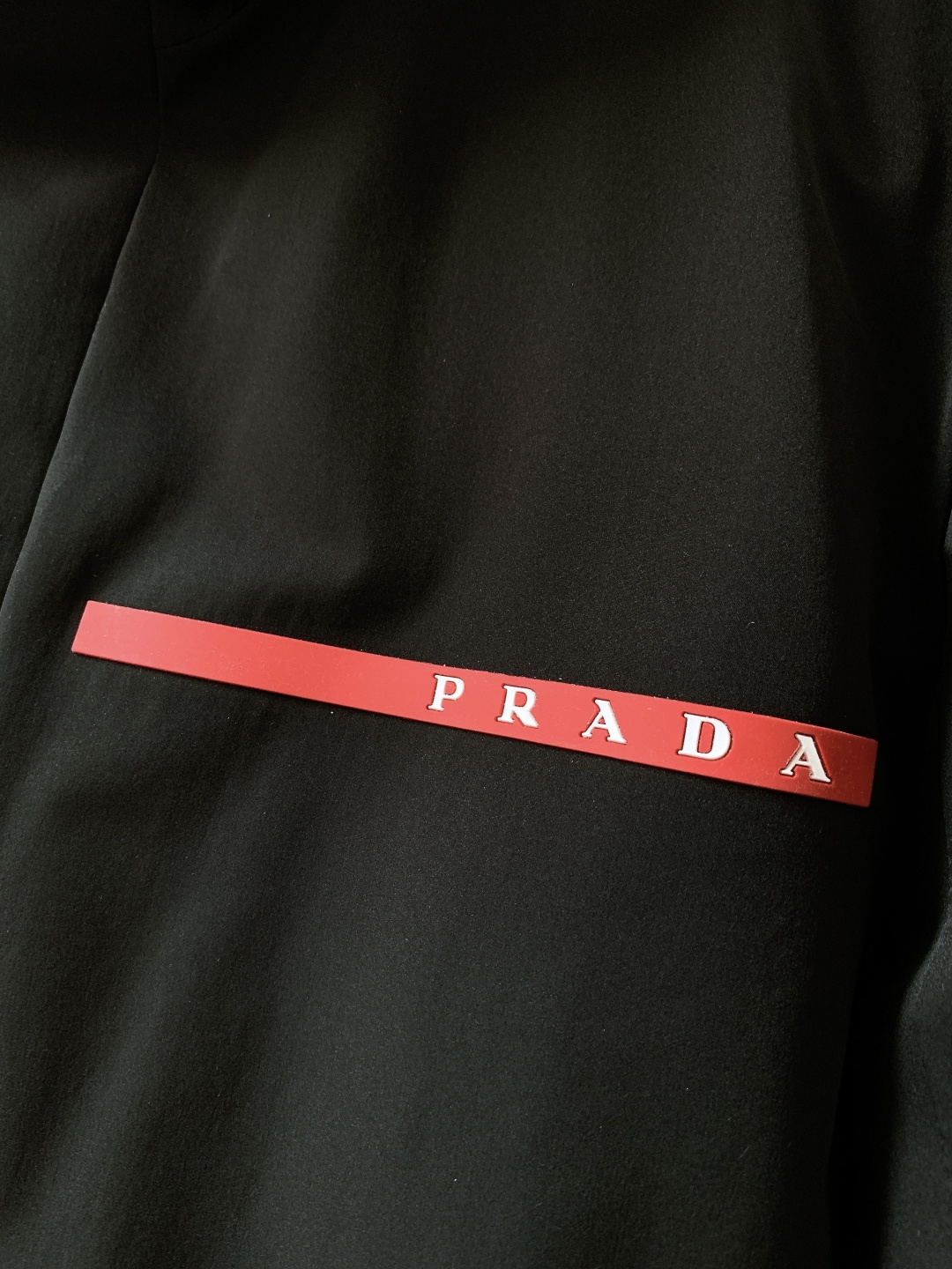 Prada 普拉达 2025FW秋冬新品中长款连帽羽绒服。采用100%再生聚酯纤维打造的三层防水面料，搭