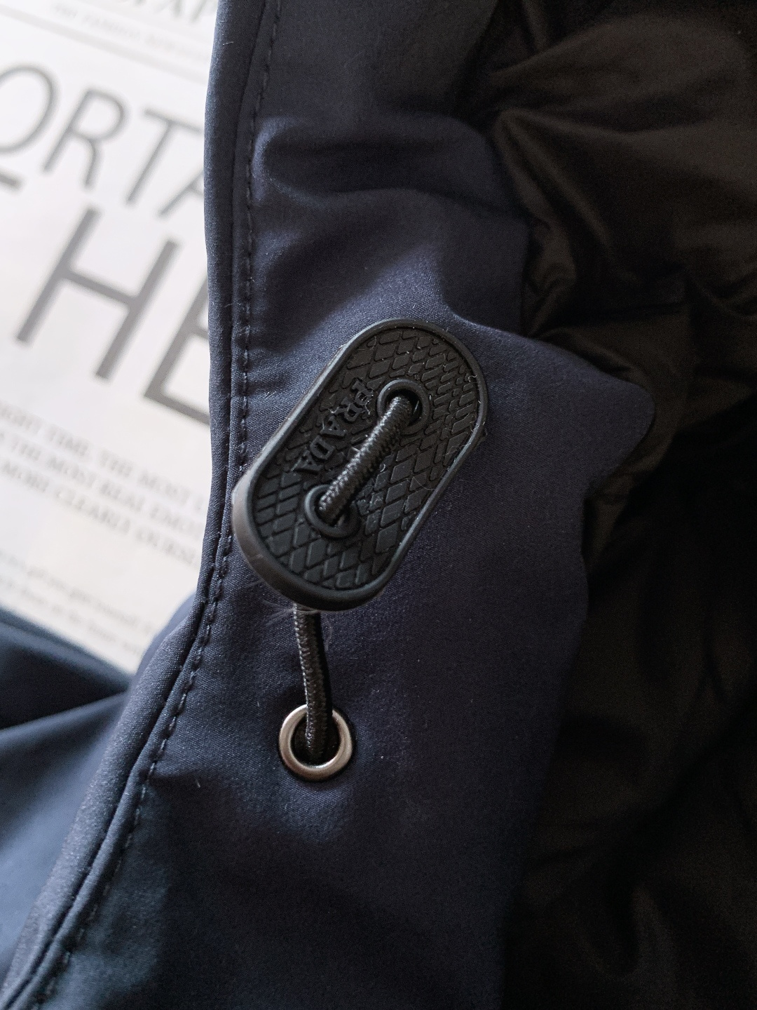 Prada 普拉达 2025FW秋冬新品中长款连帽羽绒服。采用100%再生聚酯纤维打造的三层防水面料，搭