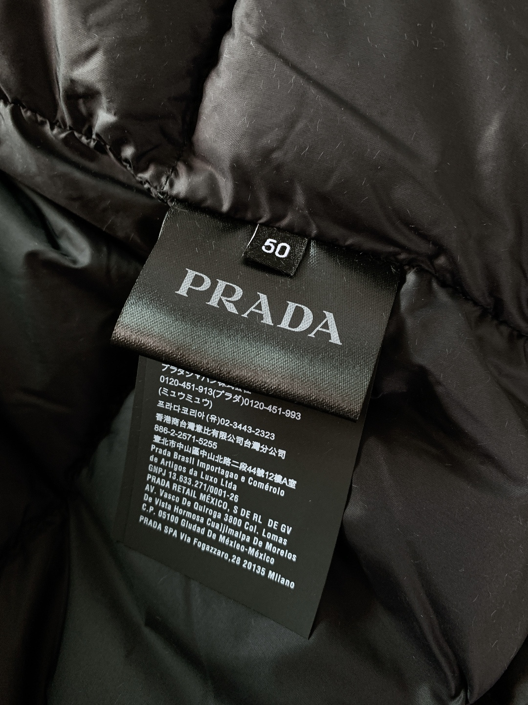 Prada 普拉达 2025FW秋冬新品中长款连帽羽绒服。采用100%再生聚酯纤维打造的三层防水面料，搭