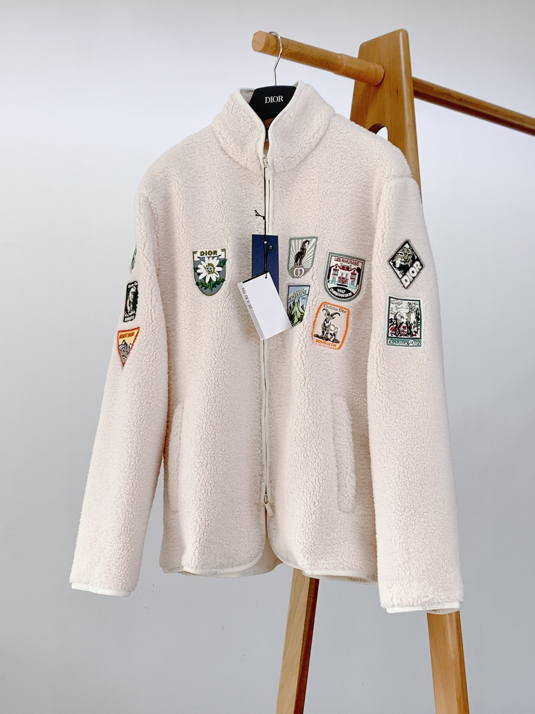 NO:692434,Dior Homme 2026SS early spring new product casual fleece jacket. This Dior Mountain fleece jacket is based on ivory fleece technical fabric. The surface of the fabric presents a fine and fluffy velvet feel, soft to the touch and stiff. The hemming process at the edges is neat and delicate, and the stitching is dense and even, perfectly combining the texture of the fabric with the exquisiteness of the craftsmanship.  The jacket adopts a two-way zipper opening and closing design. The metal zipper pull is engraved with clear brand letter logo. The zipper teeth are smooth and wear-resistant. It is matched with the zipper edge of the same color, which not only ensures the convenience of putting on and taking off, but also makes the overall line more neat. There are welt pockets on both sides of the body, and the brand letter logo is embossed with the brand letter logo in a dark pattern on the edge of the pocket. The brand details are hidden in a low-key manner.  The multi-color embroidered patches all over the body are the core design highlights. The badge pattern combines alpine elements with Dior's classic logo. The iconic animal and plant patterns of the Alps such as edelweiss, blue sheep, and marmots are vividly matched with classic brand symbols such as '30 AVENUE MONTAIGNE' and '1947', as well as 'MONT DIOR' and 'LES'.  Mountain-themed text such as 'RHUMBS' blends Dior's high-end aesthetics with the 'alpine spirit' of the Alps. The embroidery process uses multi-color silk threads to embroider in layers. The light and dark levels and three-dimensional texture of the pattern are distinct. The outline of each badge is delicate and neat. It replicates the high-end embroidery technology in Dior's archives, making the retro badge elements the visual focus that highlights the design style.  The inside of the jacket is made of mesh fabric. The breathable mesh structure not only reduces the overall weight, but also improves air circulation when worn, and avoids the stuffiness of the fleece fabric. The label inside is clearly marked, indicating polyester fiber material, Made in Italy and other information, and the details are in line with Dior's high-end quality standards.  The loose fit is suitable for a variety of body shapes and can be layered with sweaters, sweatshirts and other items. The stand-up collar design can modify the neck line and enhance warmth. Whether worn alone or as a layer, it can keep warm while creating a very modern and fashionable look. Same style for men and women. Size S, length 68, bust 112, shoulder width 45.5, sleeve length 61, size M, length 70, chest 116, shoulder width 47, sleeve length 62  L length 72, bust 120, shoulder width 48.5, sleeve length 63, XL length 74, bust 124, shoulder width 50, sleeve length 64…19860909Dior Homme 迪奥·桀傲 2026SS早春新品 休闲抓绒夹克.这款Dior Mountain起绒夹克以象牙色起绒科技面料为基底,面料表面呈现出细腻蓬松的绒感,触感柔软且兼具挺括度,边缘处的包边工艺工整细腻,针脚密实均匀,将面料的质感与工艺的精致感完美结合. 夹克采用双向拉链开合设计,金属拉链头刻有清晰的品牌字母标识,拉链齿顺滑耐磨,搭配同色系的拉链包边,既保证了穿脱的便捷性,又让整体线条更显利落.衣身两侧设有贴边口袋,口袋边缘暗纹压印品牌字母标志,低调中暗藏品牌细节巧思. 衣身缀满的多色刺绣补丁是核心设计亮点,徽章图案融合了高山元素与Dior经典标识雪绒花、岩羊、旱獭等阿尔卑斯山标志性动植物纹样栩栩如生,搭配“30 AVENUE MONTAIGNE”“1947”等品牌经典符号,以及“MONT DIOR”“LES RHUMBS”等高山主题文字,将迪奥的高订美学与阿尔卑斯山的“高山精神”相融. 刺绣工艺采用多色丝线分层绣制,图案的明暗层次与立体肌理感鲜明,每一枚徽章的轮廓锁边都细腻工整,复刻了Dior档案中的高订刺绣工艺,让复古的徽章元素成为彰显设计格调的视觉焦点. 夹克内里采用网眼织物面料,透气的网眼结构既减轻了整体重量,又提升了穿着时的空气流通性,避免了起绒面料的闷感.内里的标签标注清晰,注明聚酯纤维材质、意大利制造等信息,细节处契合迪奥的高端品质标准. 宽松的版型适配多种身形,可内搭针织衫、卫衣等单品叠穿,立领设计能修饰颈部线条并增强保暖性,无论是单穿还是作为叠搭层次,都能在兼顾保暖的同时,打造出极具现代感的时尚造型.男女同款. S码衣长68 胸围112 肩宽45.5 袖长61 M码衣长70 胸围116 肩宽47 袖长62 L码衣长72 胸围120 肩宽48.5 袖长63 XL码衣长74 胸围124 肩宽50 袖长64 …………………………………………………… SizeS-XL,,dior,dior,hoodie,sweatshirts,jackets & coats,,Men's clothing