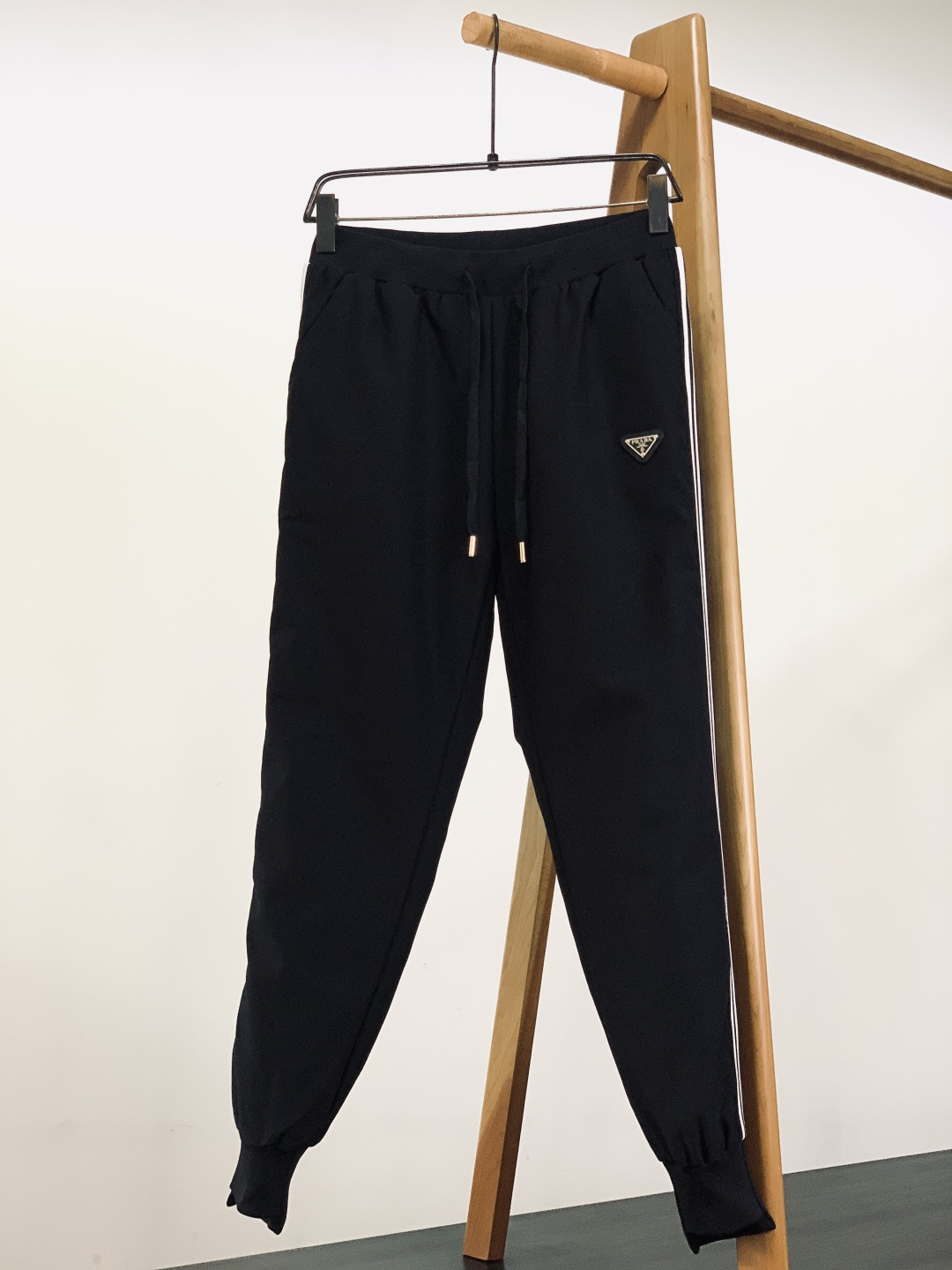 Prada 普拉达 2025FW秋冬新品休闲织带羽绒裤，经典三角徽标彰显品牌辨识度，侧边白条纹勾勒利落线