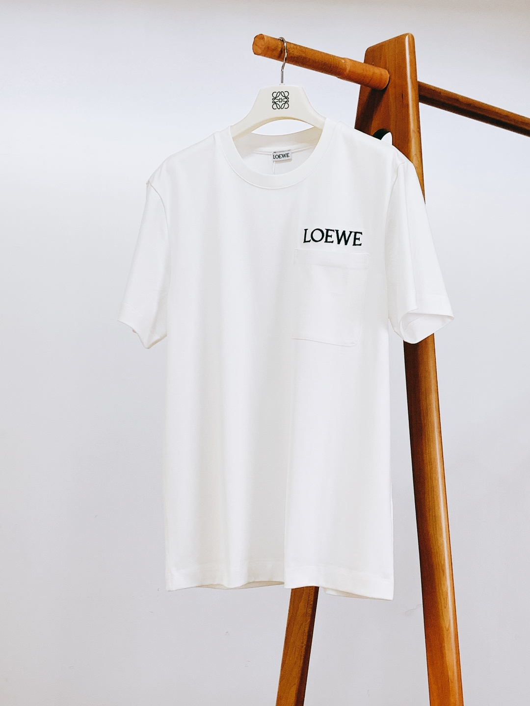 NO:726108,Support Loewe 2026SS early spring new products after the new year  Embroidered cotton loose T-shirt. It is made of high-weight combed cotton fabric, which is more stiff and less prone to wrinkles and deformation than light cotton fabrics. At the same time, it retains the soft, waxy and breathable characteristics of cotton. It does not feel stuffy when worn close to the body, and the shape is more three-dimensional when worn alone.  The three-dimensional patch pocket on the chest is a design that is both practical and decorative. The double-needle hemming process at the pocket is neat and the edges are burr-free. It can not only place small items, but also make the body more layered. The letter logo embroidery above the patch pocket is in the same color /  Contrasting color embroidery thread, fine and full stitches, no skipping threads, and accurate font proportions to restore the brand logo. It is full of three-dimensionality but not exaggerated, and low-key highlights the brand recognition. Classic round neck with reinforced hemming design, ribbed neckline for comfortable elasticity  It is medium-sized and does not loosen or curl after long-term washing. It fits the neck without feeling tight. The woven label on the inside is clearly printed and the brand information is complete. The overall design combines practicality with light luxury details. It is a high-end basic item that can be worn alone in summer or layered in spring and autumn.  ……………………………………………………………… SizeM-3XL,,loewe,loewe,tees,t-shirt,19860909支持年后 Loewe 罗意威 2026SS早春新品 刺绣棉质宽松T恤.采用高克重精梳棉面料,相较于轻薄棉料更具挺括度,不易起皱变形,同时保留棉质的软糯透气特性,贴身穿无闷感,单穿时版型更立体.胸前立体贴袋为实用与装饰兼具的设计,袋口双针锁边工艺工整,边缘无毛刺,既可以放置小物件,又让衣身层次更丰富.贴袋上方的字母标识刺绣采用同色系/撞色绣线,针脚细密饱满、无跳线脱线,字体比例精准还原品牌标识,立体感十足却不浮夸,低调彰显品牌辨识度.经典圆领搭配加固包边设计,罗纹领口弹性适中,久洗不松垮、不卷边,贴合颈部无勒感,内侧织唛标印字清晰,品牌信息完整.整体设计将实用与轻奢细节融合,是夏日单穿、春秋叠穿的高阶基础款单品. …………………………………………………… SizeM-3XL,,loewe,loewe,tees，t-shirt,,Men's clothing