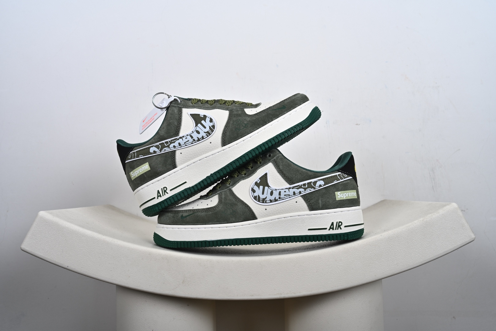 本地💰250优势放店
街头图腾，潮范新生｜Air Force 1 Low x Supreme 联名款重磅来袭！当街头潮牌的顶流Supreme邂逅Nike经典的Air Force 1 Low，这双联名款以硬核的街头美学，为经典鞋型注入全新的潮流灵魂。作为街头文化与运动传奇的跨界碰撞，它将Supreme的叛逆基因与AF1的经典底蕴完美融合，成为潮人鞋柜中不可错过的收藏级单品。鞋身以灰绿为主调，磨砂皮质的质感细腻高级，与米白色皮革拼接出极具层次感的视觉效果。鞋侧的Swoosh标志被Supreme标志性的涂鸦字体覆盖，张扬的设计瞬间打破沉闷，成为整双鞋的视觉核心；鞋身侧边的Supreme小标、鞋舌处的品牌细节点缀，以及墨绿与草绿撞色的鞋带、鞋底，在细节处将街头潮流的个性展现得淋漓尽致。延续Air Force 1 Low的经典低帮版型，轻量化的Air气垫鞋底兼顾了日常穿搭的舒适度与实用性，无论是搭配工装裤打造硬核街头风，还是配休闲裤诠释随性潮范，这双鞋都能轻松成为造型的点睛之笔。它不只是一双鞋，更是街头文化的具象表达——将Supreme的先锋态度与AF1的传奇历史凝于一体，穿上它，便是踩在街头潮流的浪尖，每一步都自带不羁的潮酷气场。
货号：SY1388-027
尺码：36-45半-K-F2