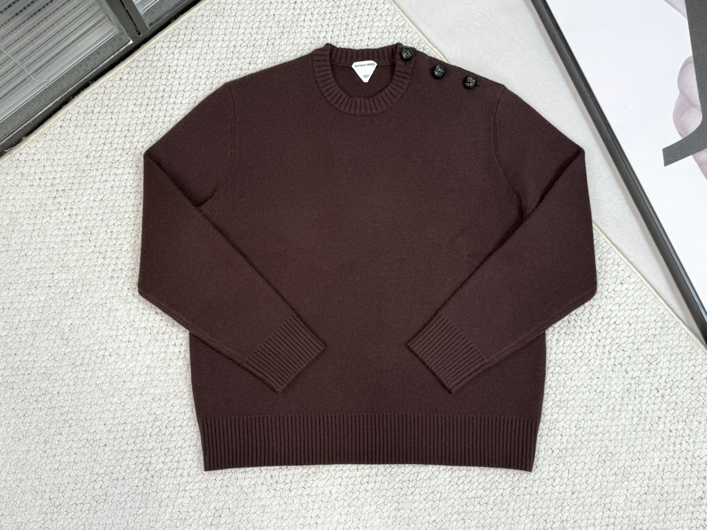 NO:531597,Product Introduction BV / Mist Red Shoulder Button Sweater 7-neck Lycra tissue round neck long-sleeved sweater, created with high-density seven-neck woven process, the fabric is tight and elastic, and the Lycra material gives it excellent elasticity and close-fitting comfort. The shoulder innovatively incorporates three genuine leather woven round buttons, which uses hand-sewing technology and sweater body to accurately combine, which not only strengthens the shoulder structure and enhances the design layering. The round neck and cuffs use a double-line edge-copying process to ensure that the wear is not deformed. The overall consideration is the exquisiteness of the craftsmanship and the functionality of the formal wear, and the leather details and knitted texture collide with the material, taking into account casual texture and light luxury details. The lazy texture item suitable for commuting and leisure, the shoulder button design cleverly enhances the shoulder line contour, making it look slim and neat, and easily controls the workplace and life scenes.,,bottega Veneta,sweaters,alexander wang19860909产品简介 BV / 枣红肩扣毛衣 7针莱卡组织圆领长袖毛衣,以高密度七针机织工艺打造,面料紧密富有弹性,莱卡材质赋予其优异回弹性和贴身舒适感. 肩头创新融入三颗真皮编织圆形纽扣,采用手工缝制工艺与毛衣本体精准结合,既强化肩部结构又提升设计层次感. 圆领与袖口采用双线拷边工艺,确保穿着不变形.整体兼顾工艺精致性与正装功能性,真皮细节与针织肌理形成材质碰撞,兼顾休闲质感与轻奢细节. 通勤休闲皆宜的慵懒质感单品,肩头纽扣设计巧妙提升肩线轮廓,显瘦利落,轻松驾驭职场与生活场景.,,bottega veneta,sweaters,alexander wang,Men's clothing