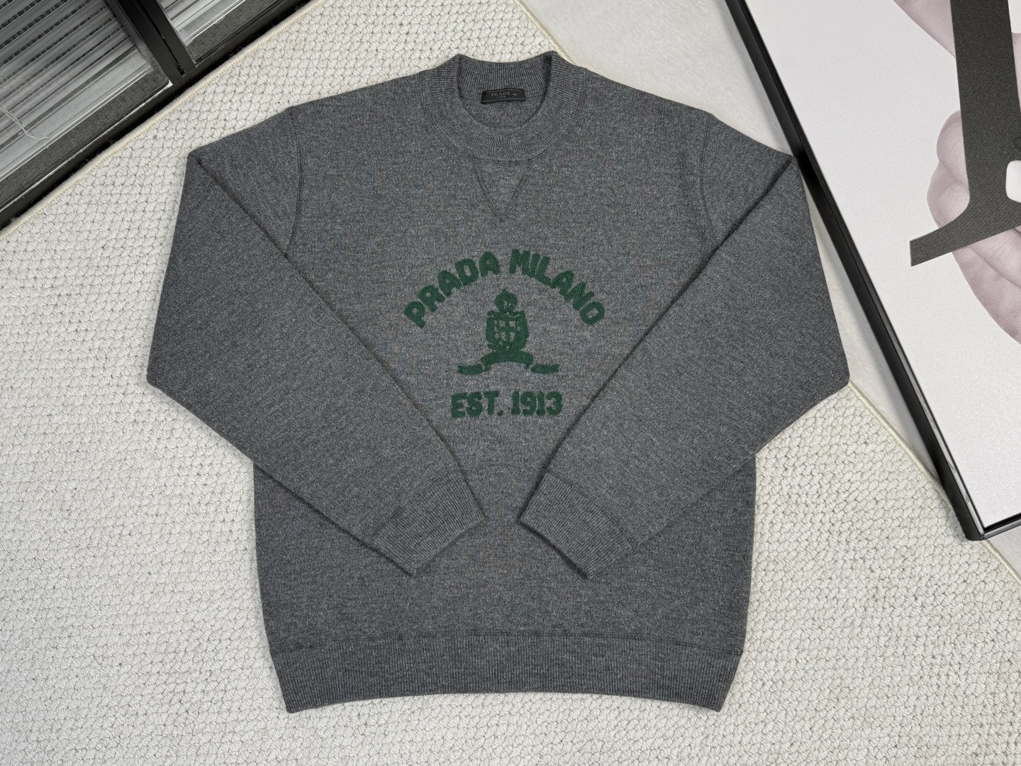 NO:531594,,Prada-Prada-Product Introduction PR / Logo Embroidery Round Neck Sweater This regular version of men's round neck sweater is made of exquisite and delicate wool materials, and the iconic triangle logo embroidery embroidery that has always been reinterpreted in a novel way, highlighting the unique brand style. The autumn and winter series uses a mix of streamlined and full shapes to portray the image of a modern man, presenting a perspective that is both synchronized and opposite to the tradition. The weaving technology is woven with a 14-needle fine needle pitch loom, with dense needles and thin yarns, making the fabric light and delicate, soft and skin-friendly, while ensuring a certain warmth and drape, suitable for layering in spring and autumn or early winter.  The neckline, cuffs and hem are closed with ribbed structure technology, which is elastic and fits the body, effectively prevents curled edge deformation, and improves wear comfort and durability. The V-neck design is reinforced by precise wiring, with neat and smooth lines, modifying the neckline and easy to match. The chain towel embroidery process is used to outline the three-dimensional velvet pattern with chain needle method, which is soft and has clear texture, injecting exquisite hand-made texture into the simple version and enhancing the visual level. The overall style is based on simple tailoring, and the fusion of weaving density, trunk functionality and embroidery decoration to achieve a balance of practicality and beauty. It is a versatile item suitable for daily commuting and leisure occasions.,,prada,prada,sweaters,alexander wang19860909,Prada-普拉达-产品简介 PR / 徽标刺绣圆领毛衣 这款常规版男士圆领毛衣采用精美细腻毛料打造,一贯以新颖方式重释的标志性三角形徽标化身刺绣,彰显与众不同的品牌格调.秋冬系列以流线和饱满形的混搭刻画现代男士形象,呈现与传统既同步又相背的视角. 织造技术采用14针细针距织机编织,针数密、纱线细,成就面料轻薄细腻、柔软亲肤的同时,保证了一定的保暖性和垂坠感,适合春秋叠穿或初冬穿着. 领口、袖口及下摆均以罗纹组织结构工艺收口,弹性佳、贴合身形,有效防止卷边变形,提升穿着舒适度与耐久性.V领设计通过精准走线加固,线条利落流畅,修饰颈线且便于搭配. 运用锁链式毛巾刺绣工艺,以链条针法勾勒出立体绒感图案,触感柔软、纹理鲜明,为简约版型注入精致手作质感,增强视觉层次. 整体风格以简约剪裁为基础,通过织造密度、罗口功能性与刺绣装饰的融合,实现实用性与美感的平衡,是一款适合日常通勤与休闲场合的百搭单品.,,prada,prada,sweaters,alexander wang,Men's clothing