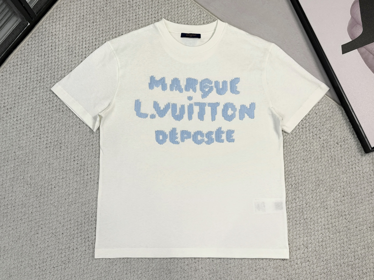NO:531600,Lv Louis Vuitton 1 Product Introduction 1V / Wool Embroidered T-shirt Fabric 12S plain cotton fabric / 230G Rib 32S double yarn rib / 350G This cotton T-shirt uses soft wool texture yarn, embroidering logos and letters at the front and back, presenting a visual effect similar to knitted texture. It is suitable for matching with various casual shapes to show full of fun and elegant style. The fabric uses 12S cotton fabric to ensure breathable and softness in daily wear. The high-density ribbed neckline enhances elasticity and resistance to deformation through double yarn structure and higher gram weight, forming a practical structure of 'main softness and auxiliary toughness'.  Embroidery pattern imitating knitted texture embroidery technology, special wool texture yarn is used, and letters are marked with tens of thousands of stitches through high-precision computer embroidery. The process simulates the knitted concave and convex texture through needle method, so that the pattern presents a three-dimensional velvet touch and visual layer, which not only retains the exquisiteness of the embroidery, but also gives it the soft beauty of the knitted fabric. Through the differentiated fabric processing and innovation of embroidery technology, exquisite details are injected into the simple version, achieving a high unity of comfort, durability and brand artistic expression, becoming an iconic item that takes into account daily practical wear and low-key luxury style.,,louis vuitton,louis vuitton,tees,t-shirt,alexander wang19860909Lv 路易威登1产品简介 1V / 毛线刺绣T恤 面料12S平纹纯棉面料 / 230G 罗纹32S双纱拉架罗纹 / 350G 本款棉质T恤选用柔软羊毛质感纱线,于前后分别刺绣标识和字母,呈现恰似针织肌理的视觉效果.适宜搭配各式休闲造型,彰显盎然趣味与优雅格调. 面料采用12S棉质面料保证日常穿着的透气柔软性,领口高密罗纹通过双纱结构与更高克重提升弹性与抗变形能力,形成“主柔辅韧”的实用架构. 刺绣图案仿针织肌理刺绣工艺,选用特殊羊毛质感纱线,通过高精度电脑刺绣将字母标识以数万针脚密绣成型.工艺通过针法模拟针织凹凸纹理,使图案呈现立体绒感触觉与视觉层次,既保留刺绣的精致度,又赋予其编织物的柔和美感. 整体通过面料差异化处理与刺绣工艺创新,在简约版型中注入精湛细节,实现舒适性、耐久性与品牌艺术表达的高度统一,成为兼顾日常实穿与低调奢华格调的标志性单品.,,louis vuitton,louis vuitton,tees，t-shirt,alexander wang,Men's clothing