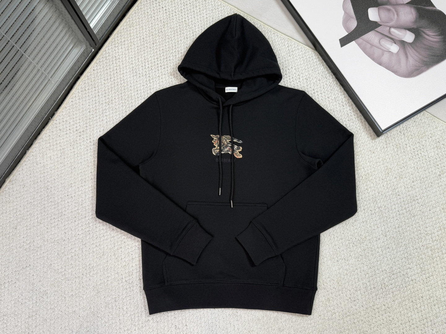 NO:530527,Product Introduction Burberry / Equestrian Knight Logo Plaid Cotton Hoodie Fabric 26S Double Yarn, Bottom 10S Fleece Yarn / 570G Rib 21S Double Yarn / 470G Make it from flipped terry cotton fabric to present a slim fit; embroidered with brand logo and equestrian Knight logo embroidery, plaid pattern as the background, interpreted in the iconic sand beige. Cotton terry wool fabric is a knitted fabric made of all cotton, which forms a short layer of fluff on the surface of the fabric through brushing and wooling processes. The advantages of this fabric are soft texture, good breathability, good moisture absorption, and no static electricity. It also has a certain elasticity, which can maintain the shape of the clothes well. In addition, the cotton terry wool fabric also has good warmth and can effectively lock the temperature and keep warm.  The letters on the front chest and the equestrian knight logo are all made of high-density multi-color embroidery technology, with clear and three-dimensional edges; the most breakthrough is the use of classic plaids to replace traditional weaving as the pattern background, giving classic elements a new touch and layering through the embroidery texture, realizing the artistic effect of painting with embroidery. Drawstring hoods, rib knitted edges and velvet storage pockets are reinforced and sewn to enhance functional durability; injecting restrained British style in casual sports. The overall perfect balances the contemporary transformation of classic symbols, the comfort of wearing and daily practicality, becoming a model for interpreting the casual style of modern elites., burberry, hoodie, sweatshirts, hats, alexander wang19860909产品简介 巴宝莉 / 马术骑士徽标格纹棉质连帽衫 面料26S双纱、底10S绒纱/ 570G 罗纹21S双纱 / 470G 选用翻面毛圈绒棉质面料打造,呈现修身版型；点缀品牌徽标和马术骑士徽标刺绣,采用格纹图案作为背景,以标志性沙米色演绎. 棉质毛圈绒卫衣面料是一种由全棉制成的针织面料,通过拉绒、起毛等工艺使面料表面形成一层短短的绒毛.这种面料的优点在于质地柔软、透气性好、吸湿性好、不起静电,同时还具有一定的弹性,可以很好地保持衣物的形状.此外,棉质起绒卫衣面料还具有很好的保暖性能,可以有效地锁住温度,保持温暖. 前胸字母与马术骑士徽标均以高密度多色刺绣工艺打造,边缘清晰立体；尤具突破的是将经典格纹以刺绣方式替代传统编织作为图案背景,通过绣线肌理赋予经典元素全新触感与层次,实现以绣作画的艺术效果. 抽绳连帽、罗纹针织包边及绒里收纳口袋均采用加固缝制,强化功能耐用性；在休闲运动中注入内敛英伦格调.整体完美平衡经典符号的当代转化、穿着舒适度与日常实用性,成为诠释现代精英休闲风的典范之作.,,burberry,hoodie,sweatshirts,hats,alexander wang,Men's clothing