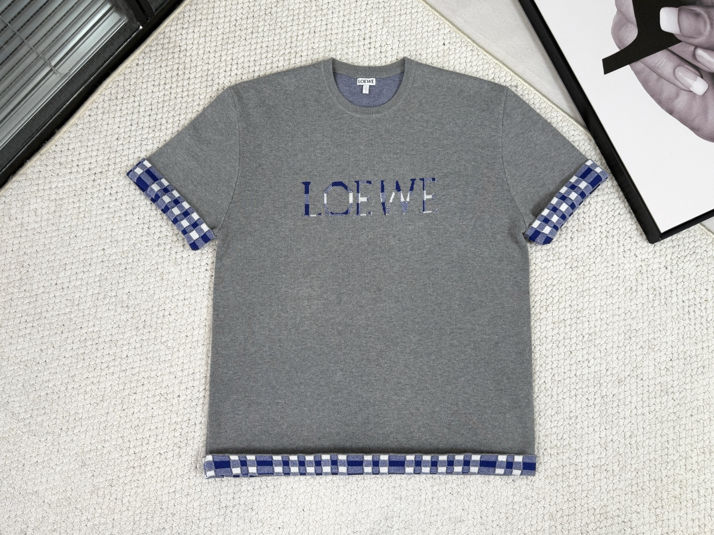 NO:540143,, Luo Yiwei/Product Introduction Lo Yiwei/Blended wool jacquard top Color brown and gray Selected wool and cotton blended yarns on the fabric, combining the warm elasticity of wool and the soft and skin-friendly of cotton, and woven through imported 124S fine needle jacquard machine. The high number of needles ensures the flower pattern accuracy, and the bottom 'seed bottom' jacquard process forms a fine dot-like texture, giving the fabric a light and compact touch and visual layer, breaking the monotonicity of jacquard. The core process lies in the integral forming of front and back jacquard. The front logo and the plaid are directly interwoven and formed through program control in weaving. The pattern and fabric are integrated, have no sense and flatness, and have excellent color fastness and durability.  The round neck woven with pit strips has stronger elasticity and resistance to deformation, ensuring that the neckline remains firm for a long time. The regular version combines the standard length to create a neat outline. The overall decoration is replaced by weaving language, symbolizing the brand into an inner texture, creating a craft work that combines the texture of the dress and a low-key luxury style.,,loewe,alexander wang19860909,罗意威/产品简介 罗意 / 混纺毛料提花上衣 颜色棕、灰 面料上精选羊毛与棉混纺纱线,兼具羊毛的保暖弹性与棉的柔软亲肤,并通过进口124S细针提花机织造.高针数确保花型精度,底层“芝麻底”提花工艺形成细微点状肌理,赋予面料轻盈紧凑的触感与视觉层次,打破了平纹针织的单调性. 核心工艺在于一体成型正反提花.正面标识与外翻的格纹,在织造中通过程序控制不同色纱直接交织成形.图案与面料浑然一体,无感平整,且具备卓越的色牢度与耐用性. 坑条组织编织的圆领具备更强弹性与抗变形能力,确保领口长期保持挺括.常规版型结合标准衣长,塑造利落轮廓.整体以织造语言取代装饰,将品牌符号化为内在肌理,成就了一件兼具穿着质感与低调奢华格调的工艺之作.,,loewe,alexander wang,Men's clothing