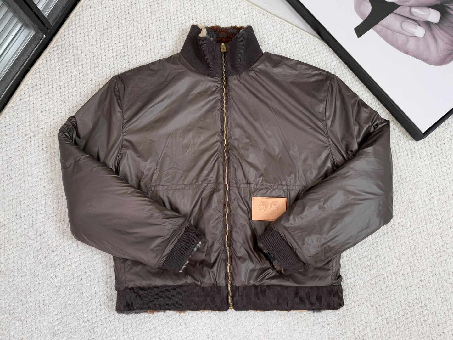 NO:540129,LV Louis Vuitton/Product Introduction 1V / Suede Double-Sided Girdle Jacket This waist jacket uses 3D suede to present the design element pattern, and incorporates Monogram elements in between. Flip it into a plain pilot jacket. PN patches commemorate creative cooperation, with VVN leather patches on both sides. This product is a turtleneck double-sided jacket that subverts traditional design. The core of the craft revolves around double-sidedness, material collision and symbolic decoration to achieve the practical aesthetic of wearing multiple clothes. The double-sided structure is the biggest highlight. The jacket adopts 3D suede technology on one side. Through precise shearing or engraving technology, three-dimensional Leo and Monogram patterns are presented on the soft base cloth, with a rich touch and a deep visual layer; the other side turns into a plain bomber jacket.  Use smooth functional fabrics to form the ultimate contrast between texture and style. The composite process of the double-layer fabric ensures clarity and warmth. The high-neck design strengthens the protection function, and the waist tailoring neatly modify the body. The detailed craftsmanship PN joint patches indicate the cooperation theme, while the VVN calf leather patches are embellished on both sides with precise die-cutting and edge sewing techniques, and the imprinted logo details are low-key and luxurious. The overall visual tension is strengthened by the contrast of material. Overall, this product uses innovative double-sided weaving, three-dimensional suede carving and precision leather details to deeply integrate practical functions with brand symbols, becoming a benchmark for both artistic and wearable flexibility., louis vuitton, louis vuitton, jackets & coats, jackets & coats, cowhide, alexander wang19860909LV 路易威登/产品简介 1V ／ 绒面双面束腰夹克 本款束腰夹克一面采用3D绒面呈现设计元素图案,其间融入Monogram 元素,翻转即可化身素净飞行员夹克.PN 贴饰纪念创意合作,两面均点缀VVN 皮革贴饰 本品是一款颠覆传统设计的高领双面外套,其工艺核心围绕双面性、材质碰撞与符号化装饰展开,实现一衣多穿的实用美学. 双面结构是最大亮点,外套一面采用3D绒面工艺,通过精准的剪绒或雕刻技术,在柔软底布上呈现立体的Leo与Monogram图案,触感丰盈且视觉层次深邃；另一面则化为素色飞行员夹克, 选用光滑功能性面料,形成质感与风格的极致对比.双层面料复合工艺确保挺括度与保暖性,高领设计强化防护功能,束腰剪裁则利落修饰身形. 细节工艺PN联名贴饰点明的合作主题,而VVN小牛皮贴饰以精准模切与边缘缝固工艺点缀于双面,压印标识细节低调奢华.通过材质对比光面皮革强化整体视觉张力. 整体而言,本品以创新双面织造、立体绒面雕花与精工皮革细节,将实用机能与品牌符号深度融合,成为兼具艺术性与穿戴灵活性的标杆之作,,louis vuitton,louis vuitton,jackets & coats,jackets & coats,cowhide,alexander wang,Men's clothing