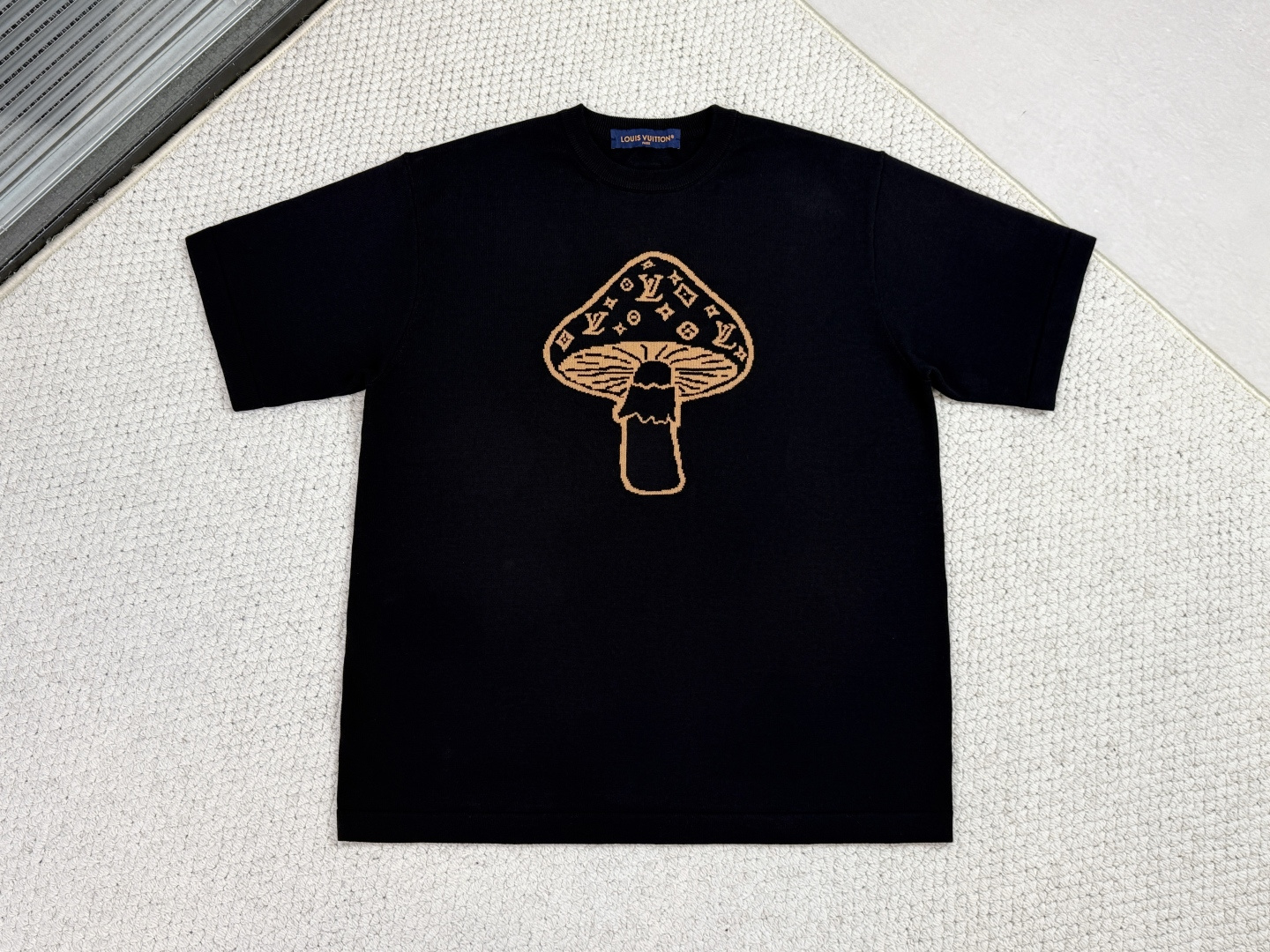 NO:610209,LV-Product Introduction 1V / Mushroom Short-Sleeve Intarsia Crewneck This neat T-shirt is made of fine knitted cotton, with a casual shape and fun graphics. Inspired by this season's British countryside walks, it features a playful mushroom intarsia pattern on the front, cleverly integrated into the logo. A woven label on the back.  Using 12S fine knitting pieces and multi-nozzle jacquard technology, the warp and weft yarns are precisely interlaced through imported equipment to achieve a double-sided original jacquard without post-printing. The pattern is scanned logarithmically from the original original, and the yarn is environmentally friendly and fixed and dyed to ensure clear edges of the pattern and saturated and lasting colors. Because the process is complex and time-consuming, and the quality of raw cotton is extremely high, it effectively avoids the common problem of joint creases in the market.  The special soft washing process is strictly controlled throughout the process to avoid thread hooking and at the same time soften the touch of the fabric and improve the breathability of the fabric. After the treatment, the fabric retains its original width and acquires delicate smoothness and excellent deformation resistance, taking into account both drape and skinny texture.  The round neck adopts high-elastic ribbing, and the connection between the armhole and the body is finely narrowed to replace traditional sewing, which doubles the labor cost but achieves exquisite details of seamless transition. The shoulder-length straight body shape combined with the natural ductility of the yarn creates a three-dimensional and non-tight wearing experience.,, louis vuitton, T-shirt, tees, t-shirt, alexander wang19860909LV-产品简介 1V / 蘑菇短袖嵌花圆领衫 这款利落的T恤采用细腻针织棉料制成,休闲造型搭配趣味图形.其灵感源于本季的英伦乡间漫旅,正面饰有俏皮的蘑菇嵌花图案,并巧妙融入标识.背面饰有梭织标签. 采用12S细针织片与多纱咀提花技术,通过进口设备进行经纬纱线精准交错,实现无需后印的双面原衣提花.图案通过原版扫描对数画花,纱线经环保固色定染,确保花型边缘清晰、色彩饱和持久.因工艺复杂耗时,且对原料棉品质要求极高,有效规避了市面常见的接轨折痕问题. 经过特殊柔软洗水工艺全程严格把关,在避免挂线钩机的同时,柔化织片触感并提升面料透气性.处理后织物在保留原有挺阔度的基础上,获得细腻光滑与优良抗变形能力,兼顾垂坠感与骨感. 圆领采用高弹罗纹,袖笼与大身连接处采用细密收针处理替代传统车缝,工时成本倍增但实现无缝过渡的精致细节.齐肩直身衣型配合纱线天然延展性,形成立体不紧绷的穿着体验.,,louis vuitton,T-shirt,tees，t-shirt,alexander wang,Men's clothing