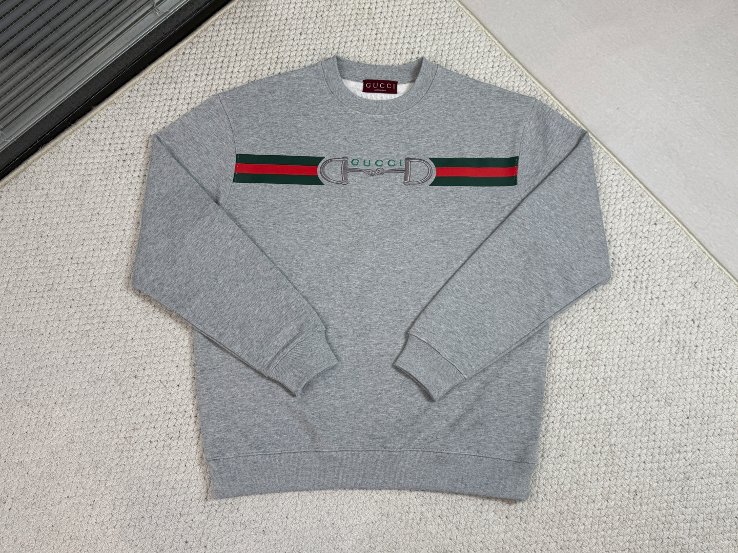 NO:712306,Gucci / Product Introduction GC / Lock embroidered knitted cotton sweatshirt. Fabric: 26 counts double yarn top layer fish scale terry bottom / 380G rib 21 counts 1x1 rib / weight 470G  It adopts a fish scale terry bottom structure and its high weight gives the garment a sculptural and crisp silhouette. The fish scale terry is precision brushed to form a thick suede surface, achieving the ultimate contrast between the outer bone texture and the inner cloud velvet touch. The collar, cuffs and hem are equipped with ultra-heavy ribbing, and its anti-deformation coefficient is greatly improved compared to conventional fabrics, ensuring that the shape remains stable after multiple wears and washes.  The classic webbing pattern is printed with environmentally friendly elastic glue, with a matte texture and a flexible touch that combines excellent elasticity and breathability. The core horsebit lock buckle uses core-covered three-dimensional embroidery technology and is covered with built-in foam core material and multiple layers of embroidery thread to create a 3D relief effect with full edges and solid touch, which has both visual tension and durability.,,gucci,hoodie,sweatshirts,19860909Gucci古奇/ 产品简介 GC / 锁扣刺绣针织棉卫衣 面料26支双纱面层支纱鱼鳞毛圈底 / 380G 罗纹21支1x1罗纹 / 克重470G 采用鱼鳞毛圈底结构,高克重赋予衣物雕塑般挺括的轮廓.鱼鳞状毛圈经精密刷绒形成厚绒面,实现外部骨感与内部云绒触感的极致对比.领口、袖口及下摆搭配超重磅罗纹,其抗变形系数较常规面料大幅度提升,确保多次穿洗后形态依然稳定. 经典织带图案采用环保弹力胶浆印花,哑光质感与柔韧触感兼顾出色弹性与透气性.核心的马衔锁扣运用包芯立体刺绣工艺,通过内置泡棉芯材与多层绣线覆盖,塑造出边缘饱满、触感扎实的3D浮雕效果,兼具视觉张力与耐久性.,,gucci,hoodie,sweatshirts,,Men's clothing
