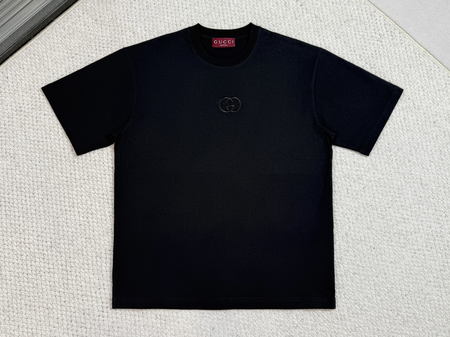NO:712309,Gucci - Product Introduction GC / Knitted cotton T-shirt with GG embroidery. Fabric: 15S special woven dense cotton fine velvet knitted fabric / 230G rib 32S high-density rib / 340G. Brand elements are cleverly integrated into the silhouette, fabric and craftsmanship, continuing the brand heritage and interpreting contemporary aesthetics. This fine velvet knitted cotton T-shirt is embellished with interlocking Double G embroidery, showing off its exquisite charm. Made of 15S specially spun dense cotton fine velvet knitted fabric, the weight perfectly balances the stiffness and skin-friendly feel. The compact spinning technology greatly reduces the yarn hairiness, and the surface of the fabric presents a delicate and smooth texture. Combined with a slight sanding treatment, it gives it a cashmere-like rich and waxy touch. The neckline is matched with 32S high-density 1×1 rib to ensure the collar's excellent resilience and deformation resistance. The interlocking double G pattern uses three-dimensional needle embroidery technology, and high-density linear stitches are closely arranged, so that the embroidery threads are naturally accumulated to form relief bulges. The embroidery surface lines are clear and sharp, and the touch is solid and full. It forms a sharp tactile contrast with the surrounding soft fine velvet fabric, showing a vivid three-dimensional feeling similar to hand-painted brushstrokes and durable quality.,,gucci,tees,t-shirt,19860909Gucci 古奇-产品简介 GC / 饰GG刺绣针织棉T恤 面料15S特纺紧密棉细绒针织面料 / 230G 罗纹32S高密罗纹 / 340G 品牌元素巧妙融入廓形、面料与工艺,延续品牌传承底蕴,诠释当代美学.这款细绒针织棉T恤缀饰互扣式双G刺绣,一展精致魅鳳力. 采用15S特纺紧密棉细绒针织面料,克重完美平衡挺括骨感与柔软亲肤性.紧密纺技术极大减少了纱线毛羽,面料表面呈现细腻光洁的肌理,配合轻微磨毛处理,赋予其羊绒般丰糯触感.领口搭配32S高密1×1罗纹,确保了领型卓越的回弹性与抗变形能力. 互扣式双G图案运用立体挨针刺绣工艺,通过高密度直线针脚紧密排列,使绣线自然堆积形成浮雕凸起.绣面线条清晰锐利、触感扎实饱满,与周围柔软的细绒面料形成鲜明的触觉对比,呈现出类似手绘笔触的生动立体感与持久耐用的品质.,,gucci,tees，t-shirt,,Men's clothing