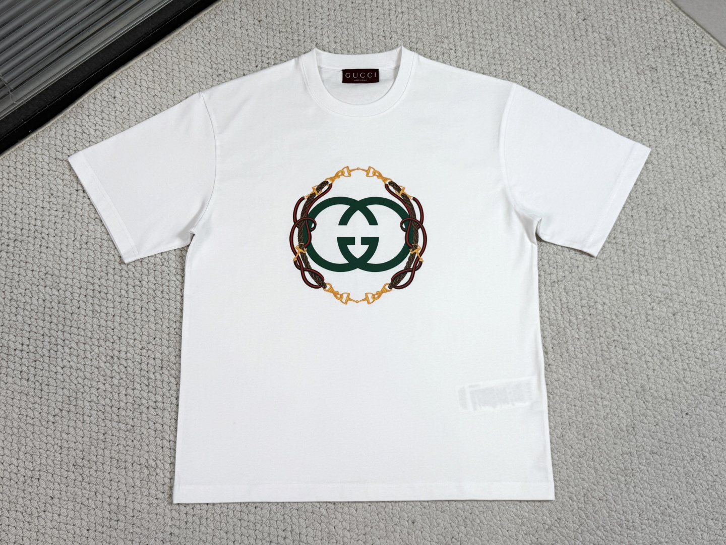 NO:712311,Gucci Product Introduction GC / Reins printed knitted cotton T-shirt Fabric 15S special woven tight fine velvet knitted cotton / 230G Rib 32S high density rib / 340G  The 2026 early spring ready-to-wear collection pays homage to the Gc fashion style, using mixed colors to interestingly combine the brand's archive elements and Florentine heritage, presenting a variety of items such as simple style and extreme design. This T-shirt is made of knitted cotton and cleverly incorporates the interlocking double G print with bridle embroidery.  It uses 15S special-spun compact fine velvet knitted cotton with a weight of 230g/㎡ to accurately balance softness, skin-friendlyness and moderate skinny texture. The compact spinning technology greatly reduces yarn hairiness, and the fabric presents a delicate and smooth texture. Combined with a slight sanding treatment, it gives it a cashmere-like soft touch. The neckline is matched with 32S high-density 1×1 rib, and the ultra-high weight of 340g/㎡ provides military-grade resilience to ensure that the collar stays stiff for a long time.  The interlocking double G reins pattern uses environmentally friendly elastic glue printing technology. The water-based environmentally friendly slurry is combined with a polymer cross-linking agent to achieve an elastic combination of the printing layer and the fabric base. This process gives the pattern a semi-matte texture and has a tensile resilience of up to 200, ensuring that the printing will not crack with the movement of the fabric. It is soft to the touch and has no sense of film hardening, perfectly maintaining the original breathability and comfort of the fabric.,, gucci, tees, t-shirt,19860909Gucci古奇 产品简介 GC / 缰绳印花针织棉T恤 面料15S特纺紧密细绒针织棉 / 230G 罗纹32S高密罗纹 / 340G 2026早春成衣系列致意Gc时尚造型,以混色搭配趣致糅合品牌典藏元素与佛罗伦萨传承意蕴,呈现简洁风格与极繁设计等多元单品.这款T恤甄选针织棉打造,巧妙融入饰缰绳刺绣互扣式双G印花. 采用15S特纺紧密细绒针织棉,230g/㎡克重精准平衡柔软亲肤性与适度骨感.紧密纺技术极大减少了纱线毛羽,面料呈现细腻光洁的肌理,配合轻微磨毛处理,赋予其羊绒般丰糯触感.领口搭配32S高密1×1罗纹,340g/㎡超高克重提供了军用级回弹力,确保领型长期保持挺括. 互扣式双G缰绳图案运用环保弹力胶浆印花技术,通过水性环保浆料与高分子交联剂配合,实现印花层与面料基底的弹性结合.该工艺使图案呈现半哑光质感,具备高达200的拉伸回弹性,确保印花随面料活动不开裂.触感柔软且无胶膜硬化感,完美保持了面料原有的透气性与舒适度.,,gucci,tees，t-shirt,,Men's clothing