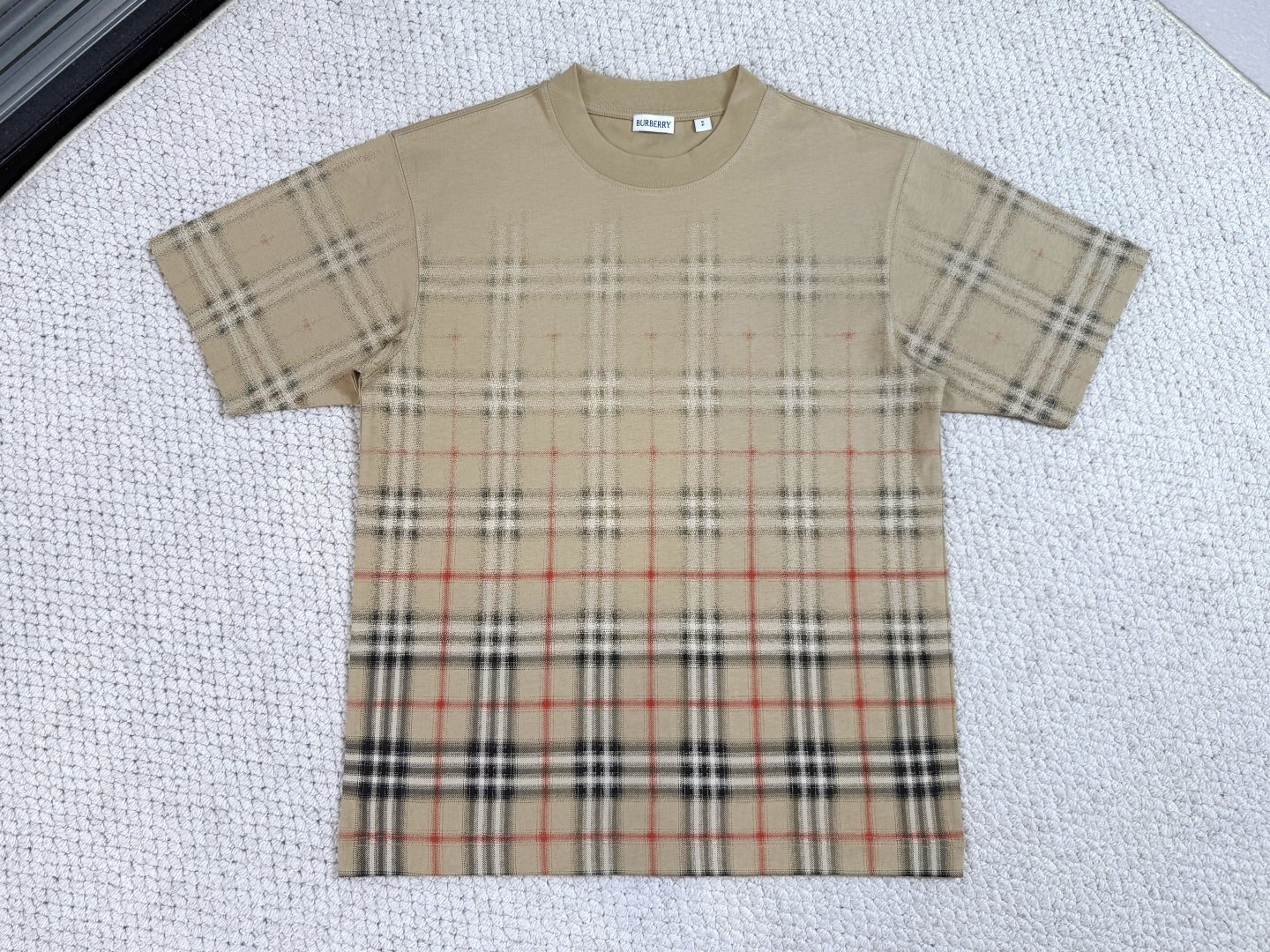 NO:712300,Product Introduction Burberry / Gradient plaid cotton T-shirt. Fabric: 15S special woven compact cotton plain fabric / 230G rib 32 count high-density 1×1 rib / 340G T-shirt, made of lightweight plain weave cotton fabric. The creativity uses a gradient style to create a printed pattern that cleverly blends plaid and solid color designs. The round neck style presents a casual fit.  Made of specially spun compact cotton plain weave fabric, the weight perfectly balances stiffness and skin-friendly breathability. The compact spinning technology reduces yarn hairiness, and the fabric presents a delicate and smooth surface texture with excellent pilling resistance. The neckline is equipped with an ultra-high weight to provide rebound support, ensuring that the collar shape remains in its original state after multiple wears and washes.  The gradient plaid uses environmentally friendly high-density dot printing technology and uses a 200-mesh ultra-high-precision screen to superimpose four-color dots. This process uses a density of more than 400 micro-color dots per square centimeter to achieve a pixel-level gradient transition, and the interface between the plaid and solid colors presents a step-free smudge effect. The thickness of the printing layer fully maintains the original breathability and softness of the fabric, and the color fastness is extremely high.,, burberry, tees, t-shirt,19860909产品简介 巴宝莉 / 渐变格纹棉质T恤衫 面料15S特纺紧密棉平织面料 / 230G 罗纹32支高密1×1罗纹 /340G T恤衫,选用轻盈平织棉质面料打造.创意采用渐变风格,营造格纹与纯色设计巧妙交融的印花图案.圆领款式,呈现休闲版型. 采用特纺紧密棉平织面料,克重完美平衡挺括骨感与亲肤透气性.紧密纺技术使纱线毛羽减少,面料呈现细腻光洁的表面肌理与卓越抗起球性.领口搭配超高克重提供回弹支撑,确保领型在多次穿洗后仍保持初始状态. 渐变格纹运用环保高密度网点印花技术,通过200目超高精度网版进行四色网点叠加.该工艺以每平方厘米超过400个微色点的密度,实现像素级渐变过渡,格纹与纯色交界处呈现无阶梯晕染效果.印花层厚度完全保持面料原生透气感与柔软度,色牢度达极高.,,burberry,tees，t-shirt,,Men's clothing