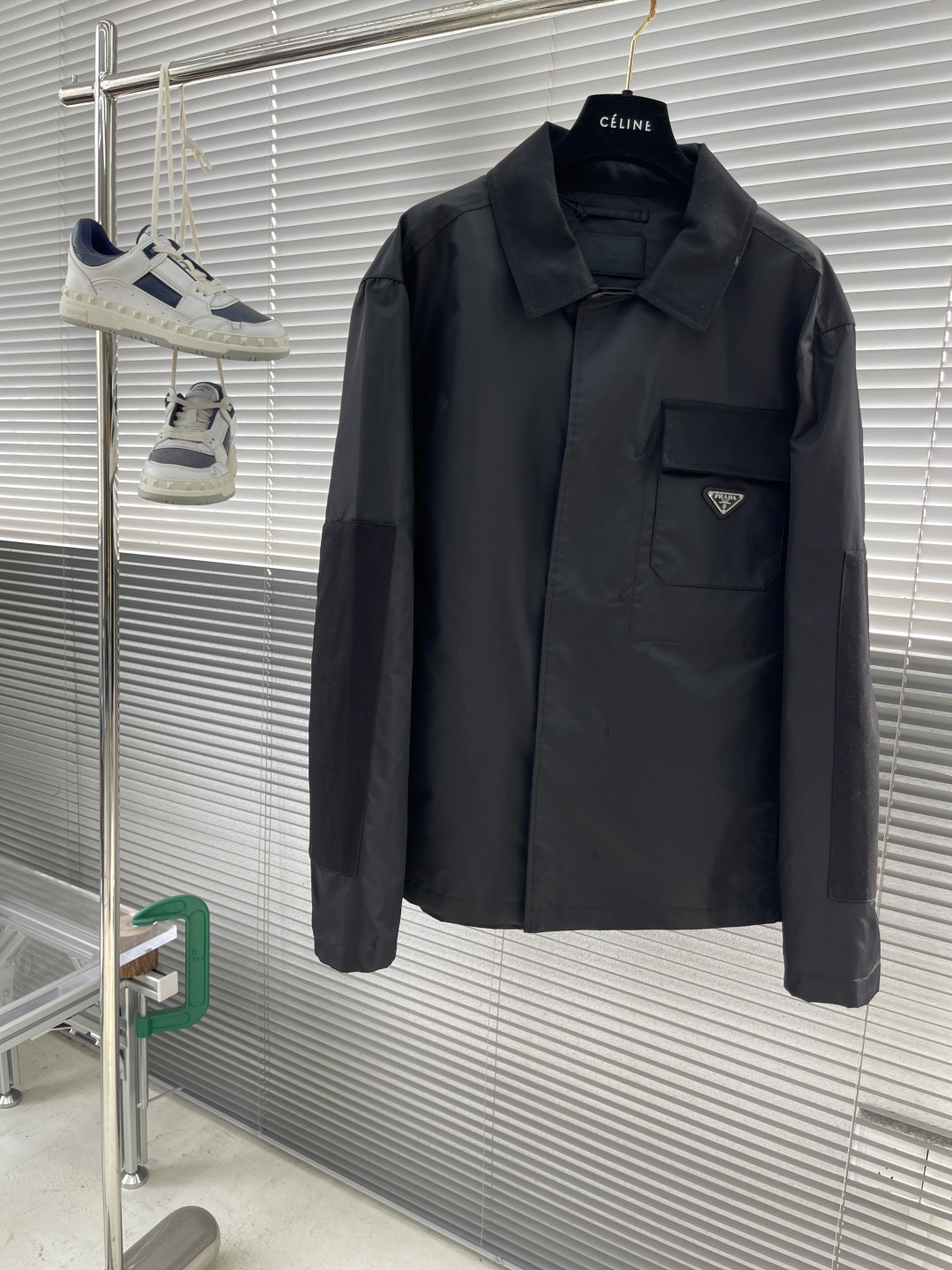 NO:938205,-PRAD regenerated nylon lapel jacket. The iconic regenerated nylon fabric has the same performance as traditional nylon. It has high strength, tear resistance, wear resistance and other properties. It is light in texture and has waterproof function, suitable for many scene needs. It is anti-wrinkle and quick-drying and is easy to care for and maintain on a daily basis.  The straight sleeves and dropped shoulders form smooth lines, and are paired with a straight hem design to highlight minimalism. The cotton twill shirt lapel contrasts with the regenerated nylon body. The softness of cotton balances the toughness and technology of nylon. The hidden snap closure makes it more aesthetic. There is a patch pocket on the left chest, with a twill plaid flap to highlight the sense of hierarchy.  , the enamel-coated triangle logo is decorated on the bag body to enhance visual recognition. The inseam pockets are integrated into the body with a hidden process, taking into account practicality and visual purity. The side pockets are reinforced at the beginning and end with pocket knotting technology to increase durability. The traditional lining is abandoned, and the stiffness of the fabric itself is used to shape the silhouette, reducing redundant layers while improving breathability.  Size S M L XL Size Clothing length Bust Shoulder width S7011649 M71120 50 L72124 5119860909-PRAD 再生尼龙翻领外套 标志性的再生尼龙面料,与传统尼龙性能相当,具备高强度,抗撕裂,耐磨损等特性.其质地轻盈,同时又具备防水功能适合多场景需求.抗皱,快干的特点也易于日常打理维护. 直筒衣袖与落肩剪裁形成流畅线条,搭配平直底边设计,凸显极简主义.采用棉质斜纹布衬衫翻领与再生尼龙主体形成质感对比,棉质的柔软亲肤平衡了尼龙的硬朗科技感.隐藏式按扣开合使其更具美感.左胸口设有贴袋,搭配斜纹格布翻盖凸显层次感,将涂珐琅三角标饰以袋体之上,强化视觉辨识度.内接缝口袋以隐藏式工艺融入衣身,兼顾实用性和视觉纯净感.侧插袋口首尾均运用口袋套结工艺加固,增加耐用性.摒弃传统衬里,以面料本身的挺括度塑造廓形,减少冗余层次的同时提升透气性. 码数S M L XL 尺码衣长胸围肩宽 S7011649 M71120 50 L72124 51 XL73128 52,,prada,jackets & coats,shirts,,Men's clothing