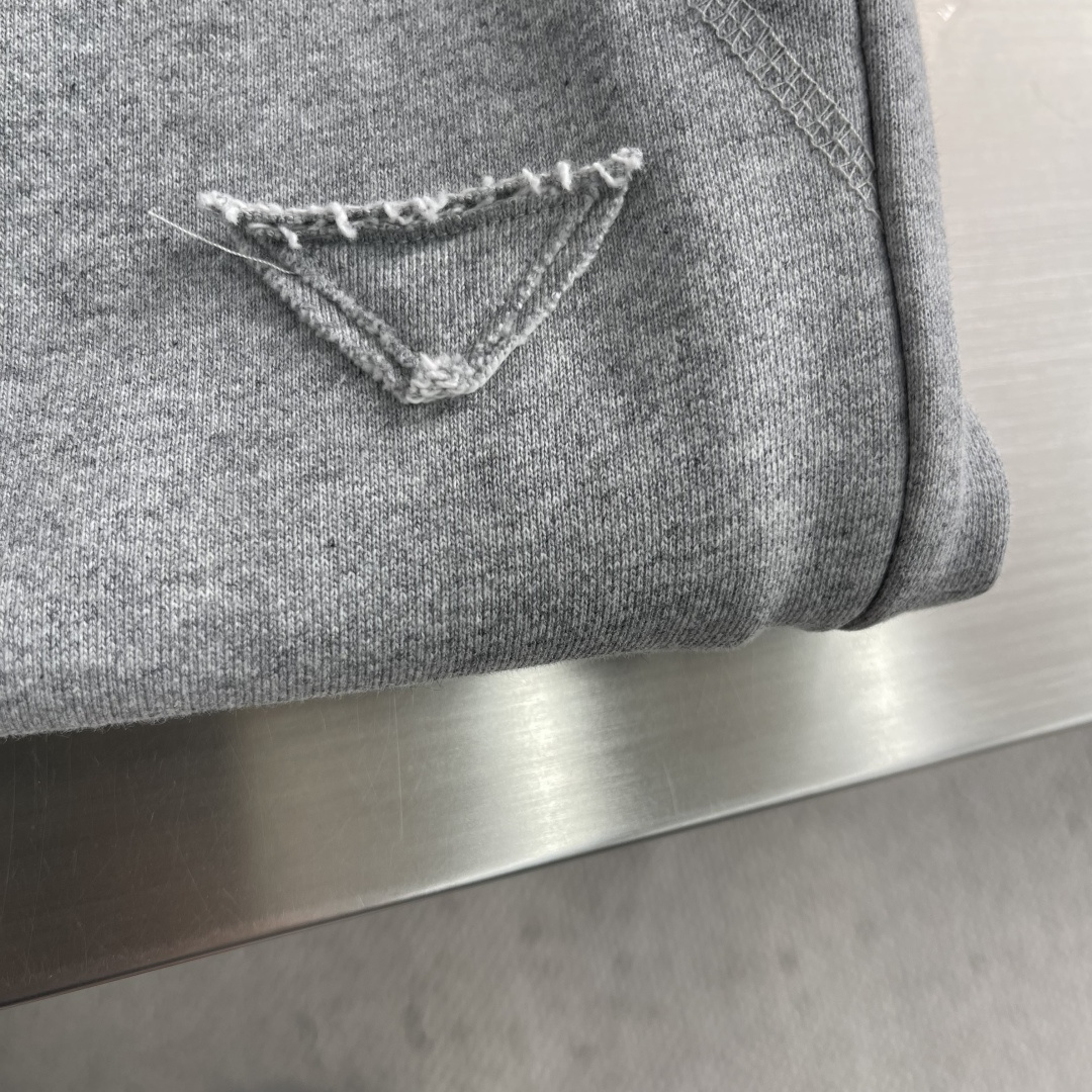 -PRAD 烧花三角标识卫裤采用380克双股鱼鳞毛圈面料，该款原版定染深花灰，搭配480克双纱同缸定染螺