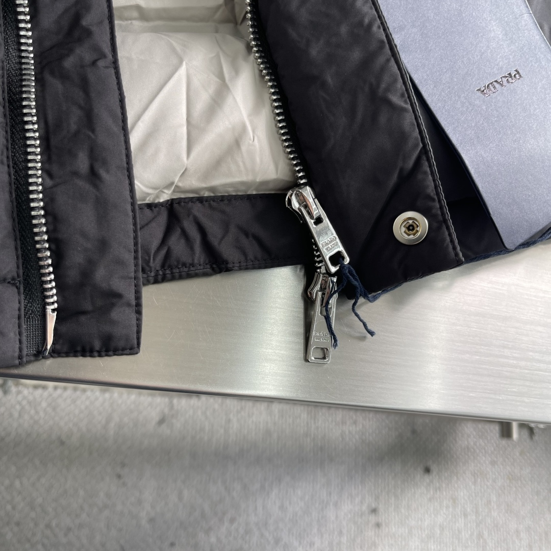 -PRAD 25年冬季新款羽绒服经典立领轻薄款，拉链口袋、袖臂三角标点缀，可调节袖口以及按扣拉链翻盖门襟
