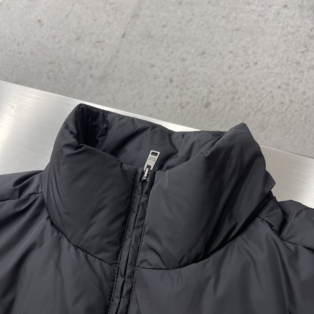 -PRAD 新款三角微标羽绒服。这款羽绒服采用新国标90白鸭绒填充而成，拉链式开合，前胸搭配有三角微标，