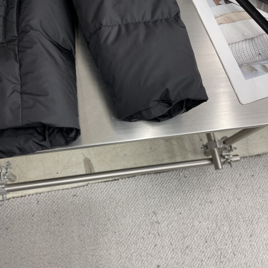 -PRAD 新款三角微标羽绒服。这款羽绒服采用新国标90白鸭绒填充而成，拉链式开合，前胸搭配有三角微标，