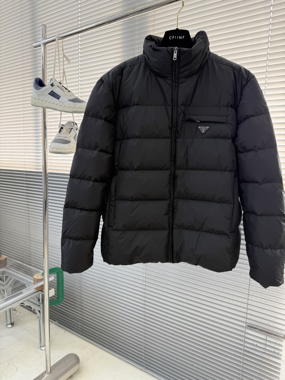 -PRAD 新款三角微标羽绒服。这款羽绒服采用新国标90白鸭绒填充而成，拉链式开合，前胸搭配有三角微标，