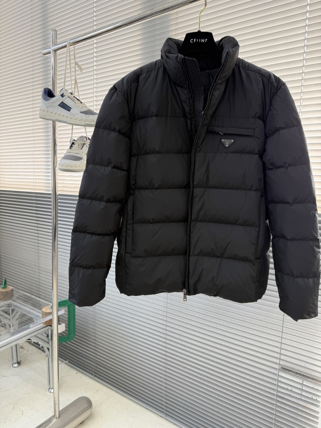 -PRAD 新款三角微标羽绒服。这款羽绒服采用新国标90白鸭绒填充而成，拉链式开合，前胸搭配有三角微标，