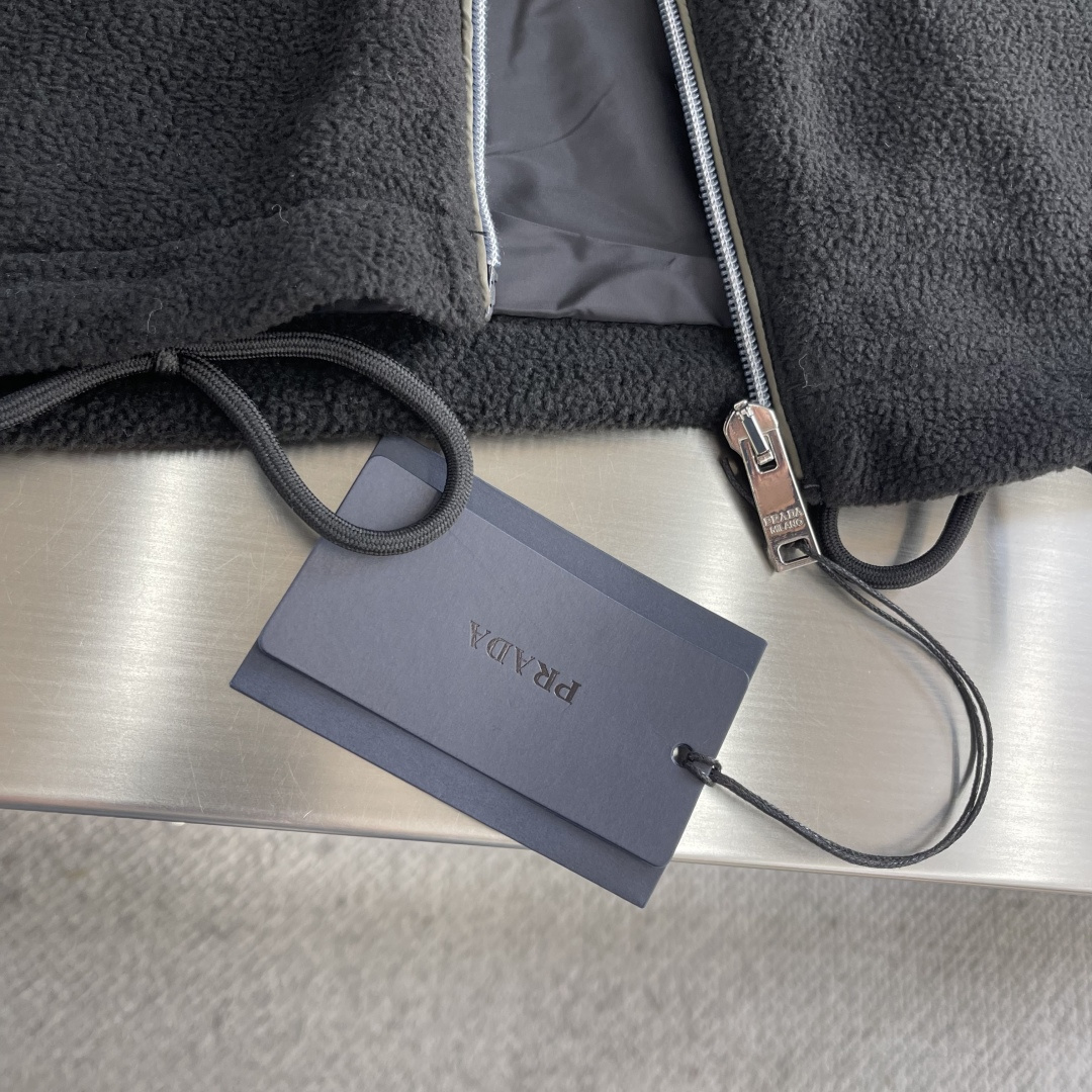 -PRAD 26ss摇粒绒夹克主要原料为聚酯纤维混纺羊毛原料经过清洗和预处理，以去除杂质。纱线通过织机织