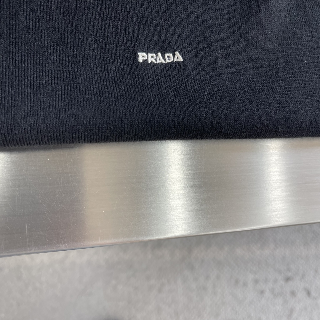 -PRAD 26SS精纺羊毛长袖采用精纺羊毛材质，这种材质具有以下特点：柔软轻盈：精纺羊毛纤维细腻，使得