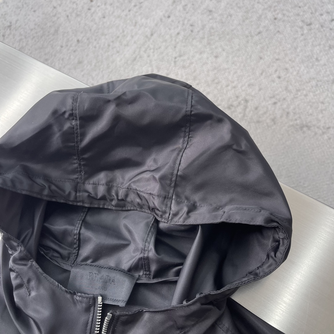 -PRAD 再生尼龙连帽夹克选用品牌标志性的再生尼龙面料，与传统尼龙性能相当，具备高强度，抗撕裂，耐磨损