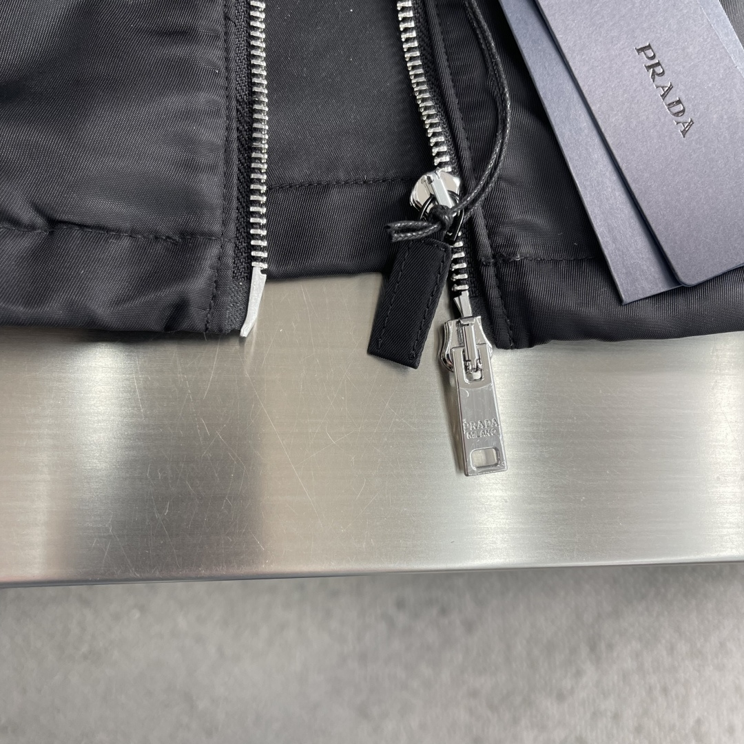 -PRAD 再生尼龙连帽夹克选用品牌标志性的再生尼龙面料，与传统尼龙性能相当，具备高强度，抗撕裂，耐磨损