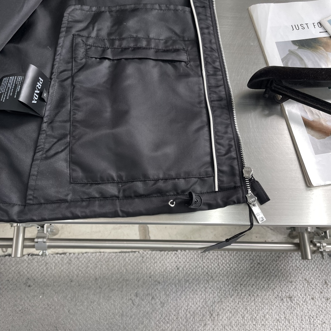 -PRAD 再生尼龙连帽夹克选用品牌标志性的再生尼龙面料，与传统尼龙性能相当，具备高强度，抗撕裂，耐磨损