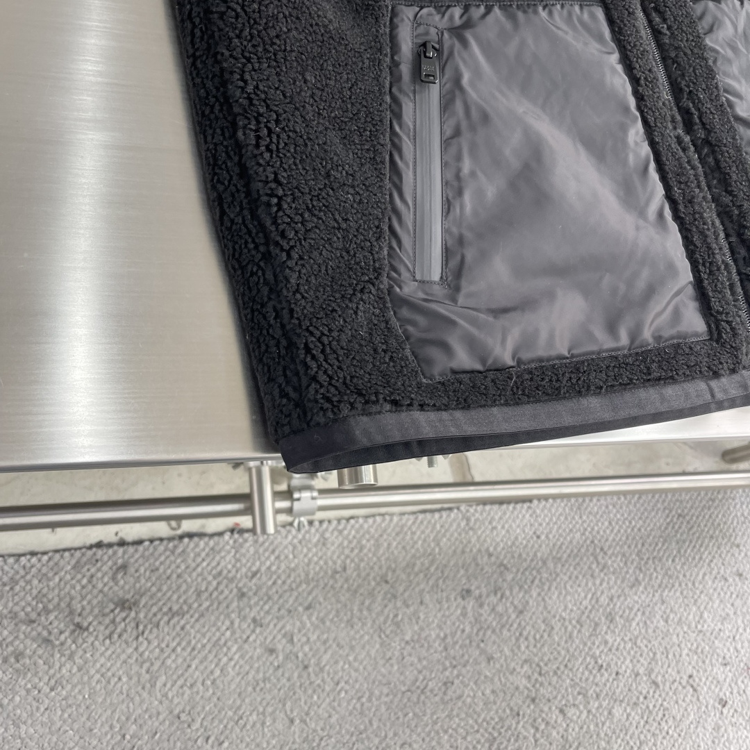 -PRAD 新款双面穿连帽夹克。这款夹克采用摇粒绒与防风面料拼接设计，兼具保暖性与机能感。胸前红色品牌标