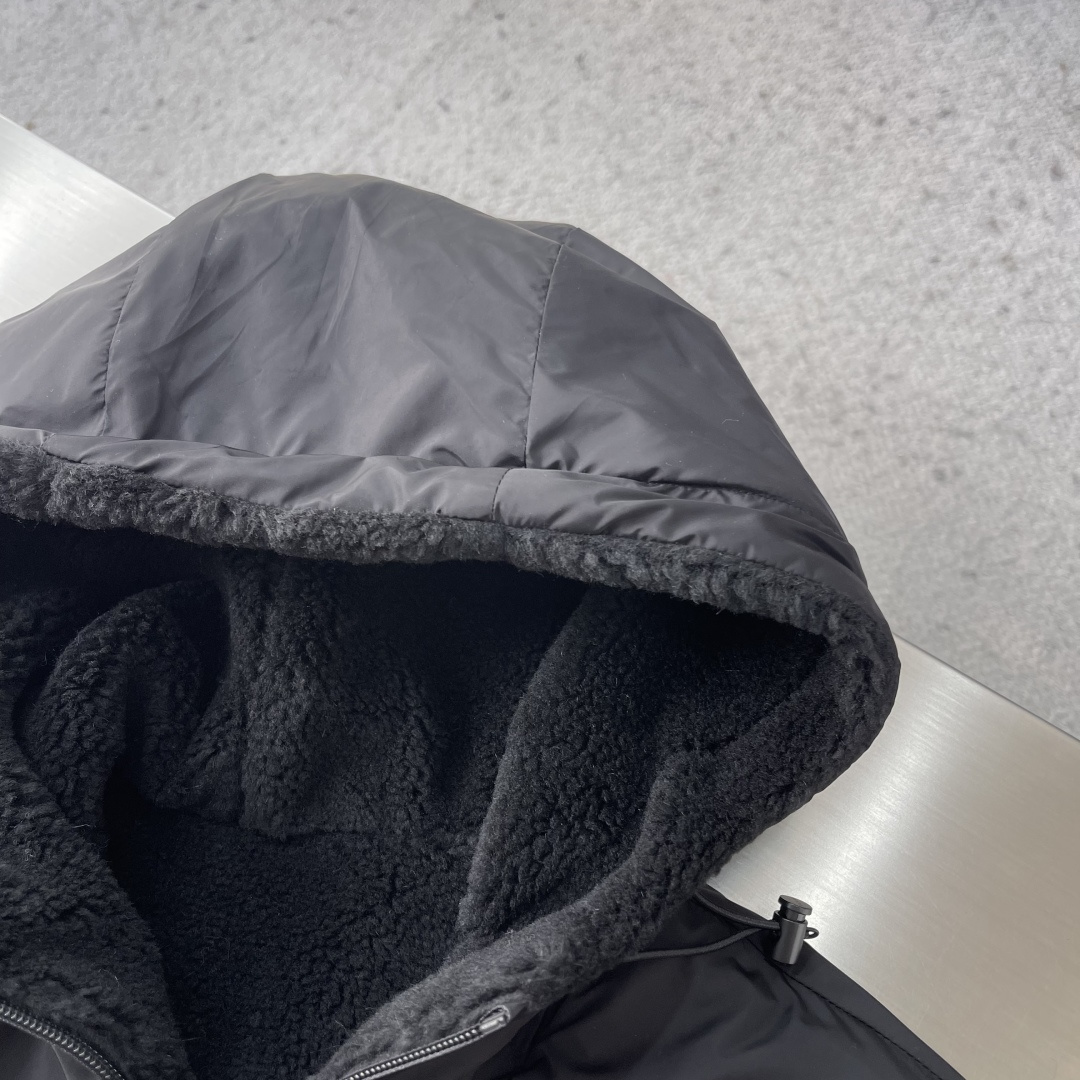 -PRAD 新款双面穿连帽夹克。这款夹克采用摇粒绒与防风面料拼接设计，兼具保暖性与机能感。胸前红色品牌标