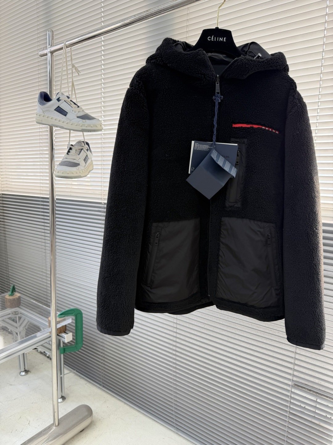 -PRAD 新款双面穿连帽夹克。这款夹克采用摇粒绒与防风面料拼接设计，兼具保暖性与机能感。胸前红色品牌标