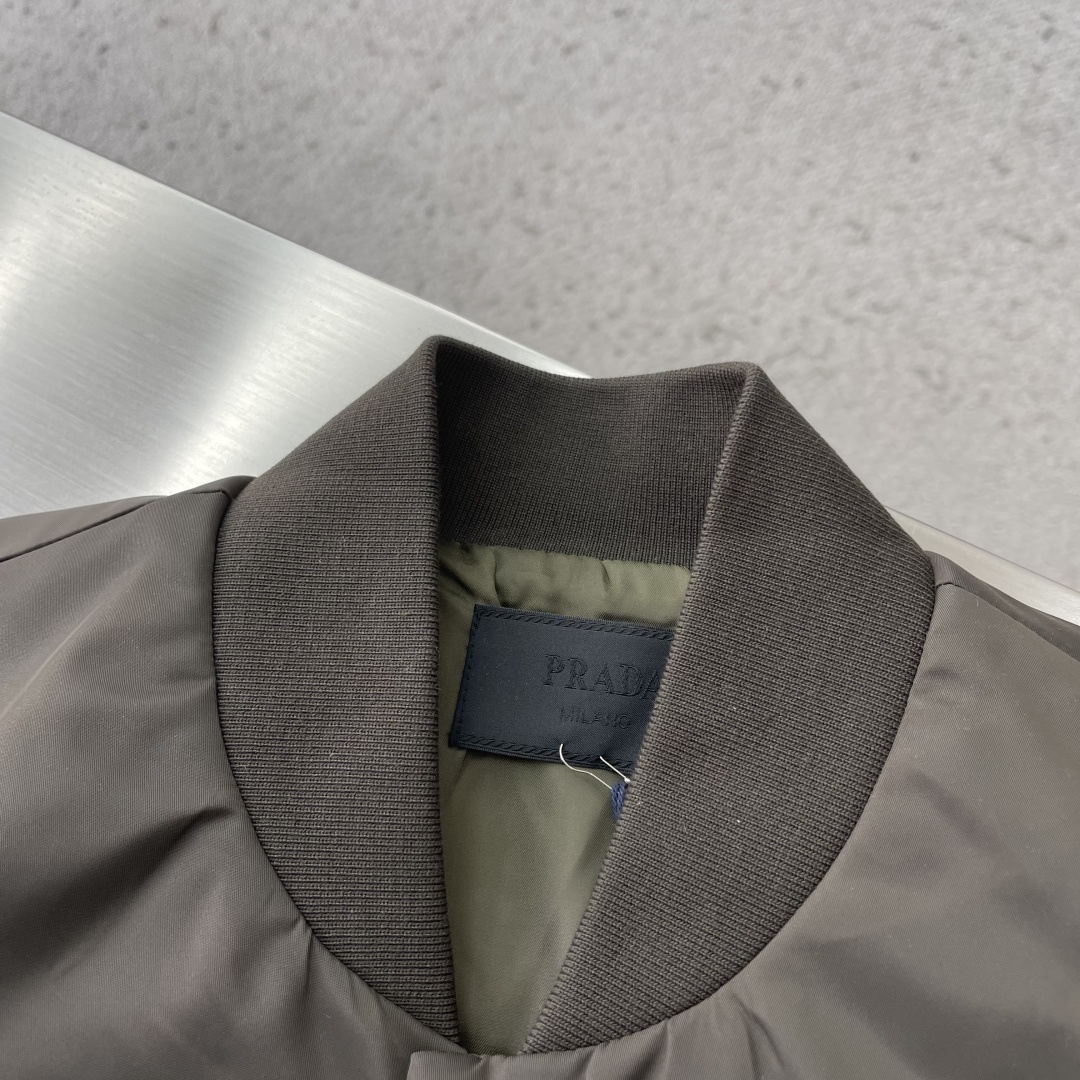 -PRAD 新款三角微标夹克。这款夹克采用高品质尼龙，罗纹领口和袖口，弹力下摆，防风防水又保暖，简约剪裁