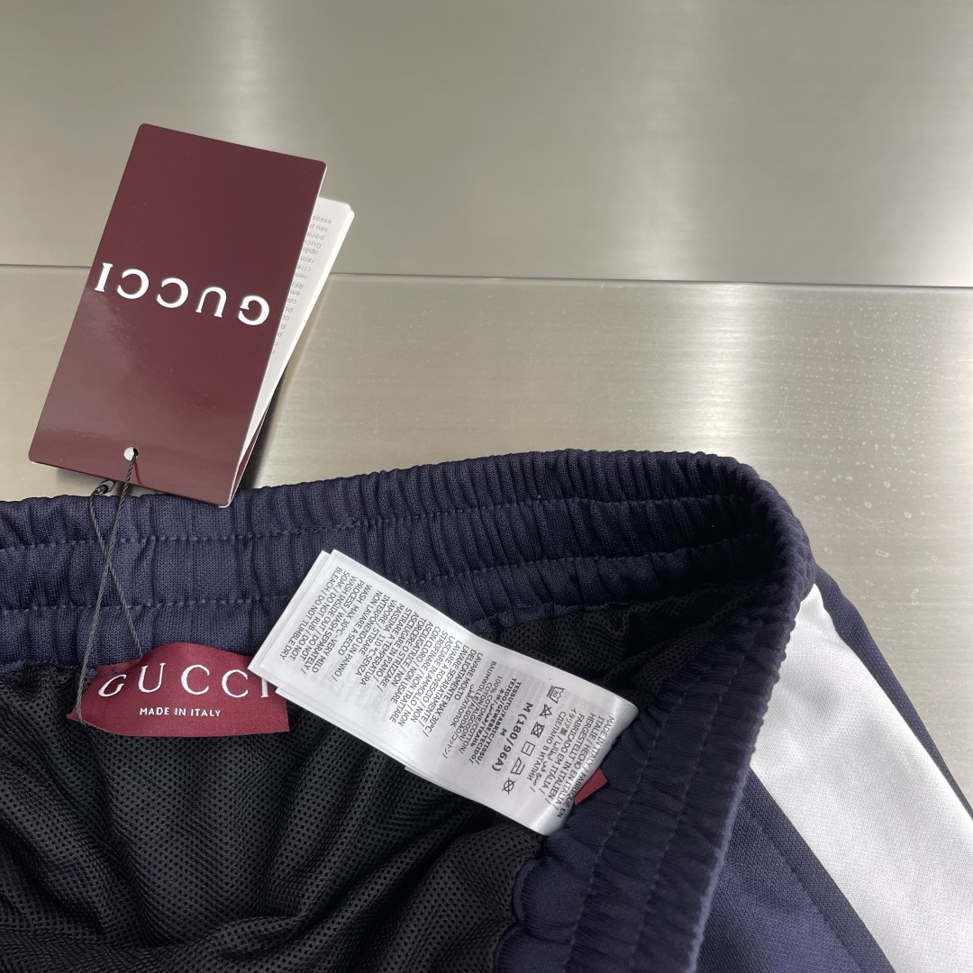 -GUCC 新款刺绣运动短裤。这款深蓝色运动短裤，侧边白色条纹+双G刺绣，品牌感满满!轻质聚酯纤维材质，