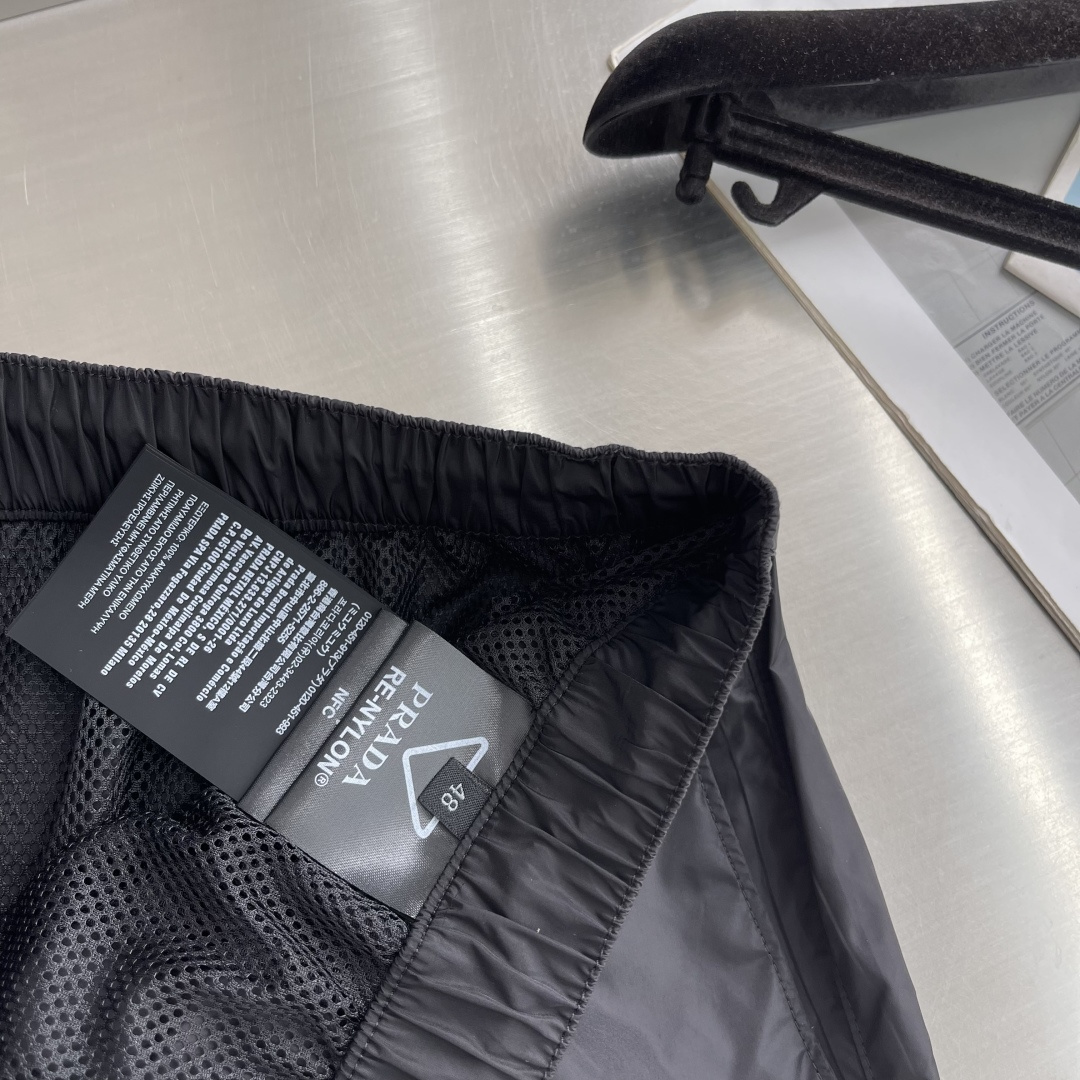 -PRAD 新款三角微标短裤。这款短裤采用流畅动感设计，选用创新的再生尼龙面料，成为Prad*系列的元素