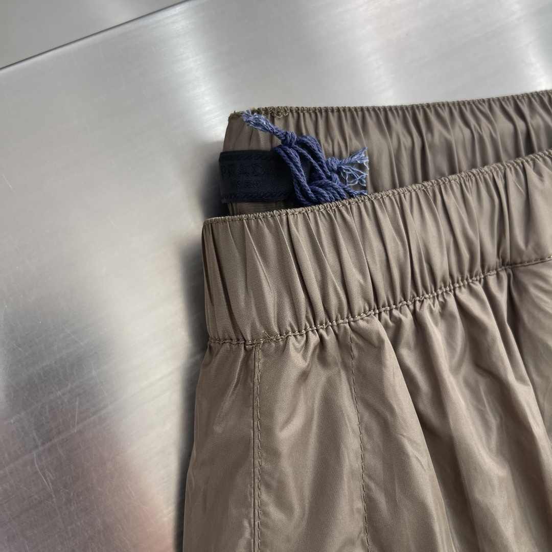 -PRAD 新款三角微标短裤。这款短裤采用流畅动感设计，选用创新的再生尼龙面料，成为Prad*系列的元素