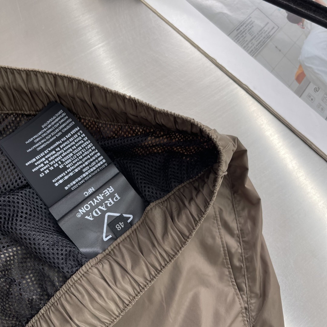 -PRAD 新款三角微标短裤。这款短裤采用流畅动感设计，选用创新的再生尼龙面料，成为Prad*系列的元素