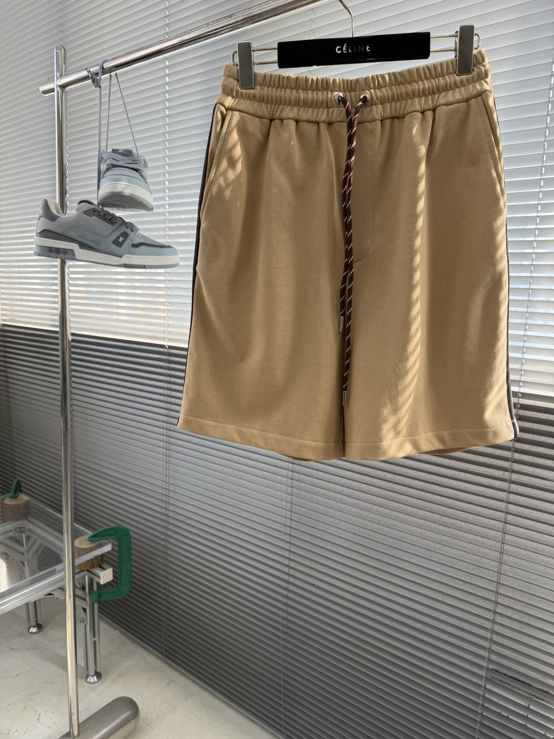 NO:870520,Shorts -mon web-trimmed knitted shorts  It is made of high-gram weight combed cotton terry fabric, using long-staple combed cotton yarn, which is formed by ring spinning + double-sided knitting weaving process. The cloth surface texture is fine and smooth, and the inner terry texture is even and dense. The high-density weaving structure makes  The fabric has both drape and stiffness and a soft and skin-friendly feel. The upper body does not cling to the legs or collapse, and has a relaxed silhouette. At the same time, the terry structure is hollow and breathable, making it dry and wicking when worn in summer, not stuffy or sticky, anti-pilling, and washable.  The fabric has been processed through three processes: pre-shrunk washing, high-temperature color fixing, and sanding and softening, which effectively solves the problems of shrinkage, color fading, and stiffness.  The waistband adopts a double-layer composite elastic weaving process, and the inner high-elastic elastic band is seamlessly spliced with the outer fabric. It is reinforced with multiple stitching lines, and the pleats are even and full, and the elasticity is long-lasting and not loose. It is equipped with a metal eyelet buckle, and the edges are edge-polished, smooth and non-scratching, and not easy to rust. The brown and white contrasting woven drawstring is customized, the rope body is tight and not easy to fluff, and the rope head adopts a laser-engraved metal head. The electroplating and polishing process has a delicate texture and smooth pulling.  The two sides of the trousers are decorated with three-color webbing, which is made of high-density polyester warp knitting. The three-color pattern is regular and clear, with moderate elasticity and is not easy to deform. During the splicing process of the webbing and the trousers, the stitching is neat and precise, the wiring is hidden and not exposed, and it is strong and not easy to unravel. The rear patch pocket is equipped with a customized metal invisible zipper, and the zipper pull is engraved with the brand logo, opening and closing smoothly without lag; the bag surface is sewn with multi-layer seams, and the bag mouth is smooth and crisp. Size SM  LXL size pants long sitting waist S52106 76 M5311080 L 5411484 XL5511888,,shorts,19860909短裤 -mon 织带饰边针织短裤 采用高克重精梳棉毛圈面料,选用长绒精梳棉纺纱,经环锭纺+双面针织织造工艺成型,布面纹理细腻平整,内里毛圈肌理均匀密实.高密织造结构让面料兼具垂坠挺括度与柔软亲肤感,上身不贴腿、不软塌,自带松弛廓形.同时毛圈结构中空透气,夏季穿着干爽排汗,不闷不粘,抗起球、耐水洗. 面料经过预缩水洗、高温固色、磨毛柔化三道工艺处理,有效解决缩水、掉色、发硬问题. 腰头采用双层复合松紧织造工艺,内层高弹橡筋与外层面料无缝拼接,经过多道车线加固,褶皱均匀饱满,弹力持久不松垮.搭配金属气眼扣,边缘做包边打磨处理,顺滑不刮绳、不易生锈；定制棕白撞色编织抽绳,绳身紧密不易起毛,绳头采用激光刻字金属头,电镀抛光工艺质感细腻,抽拉顺滑. 裤身两侧饰以三色织带,采用高密涤纶经编一体织造,三色纹路规整清晰,弹力适中、不易变形.织带与裤身拼接过程中车线工整细密,走线隐藏无外露,牢固不易开线脱边. 后置贴袋搭配定制金属隐形拉链,拉链头刻有品牌标识,开合顺滑不卡顿；袋面采用多层锁边缝制,袋口平整挺括. 码数SM LXL 尺码裤长坐围腰围 S52106 76  M5311080 L 5411484 XL5511888,,shorts,,Men's clothing