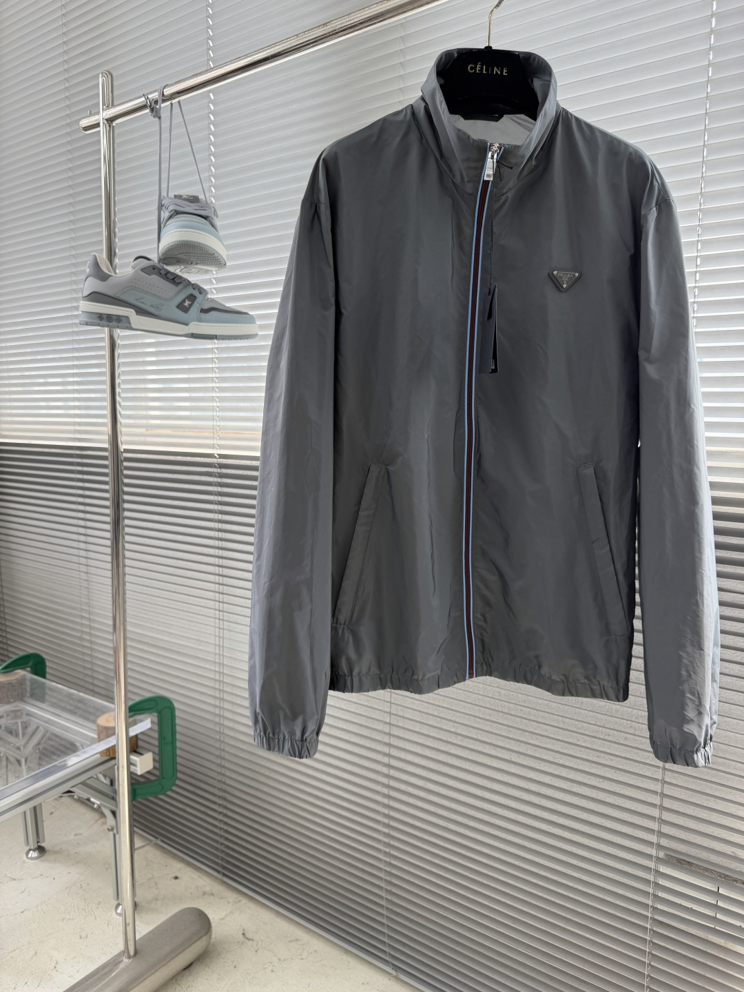 NO:912768,-PRAD zipper-trimmed stand-collar jacket is made of high-density woven nylon fabric with firm and full fiber texture. The overall texture is light and thin, with zero weight on the upper body. After the fabric is water-repellent, slight wet water will not easily adhere to it. It also has excellent stain resistance and is easy to wipe and clean daily stains. The fiber characteristics make the woven fabric excellent in toughness, tear-resistant and anti-snagging. It is not easy to wrinkle and collapse after long-term wear. It can maintain a neat and crisp silhouette even when worn for a long time, taking into account both beauty and practicality.  It adopts an embedded double-layered hemmed zipper placket, with light blue webbing wrapped on the outside of the burgundy zipper teeth, and the outer layer is wrapped with gray fabric. The zipper tape is fixed with two fine open threads, which are evenly and straightly routed, and the appearance is neat and layered. The custom-engraved metal slider drives the opening and closing. After the garment is finished, it is ironed at low temperature to smooth out wrinkles and trim threads. The placket is symmetrical and regular, and the hemming width is consistent, which not only improves windproof sealing, but also combines durability and high-end texture.  The hem and cuffs adopt double-layer elastic gathering technology. The smooth nylon fabric is folded and overlocked with elastic bands embedded inside. The double threads are evenly sewn and fixed. The stitch length is regular and fine, and the pleats are arranged evenly and naturally. The elasticity is moderate, tightening to fit the body shape without tightening the skin, effectively blocking the intrusion of wind and rain, and improving the windproof and temperature locking effect. Size SMLXL Size Clothes Length Bust Shoulder Width S69 51 M 70.5 122  52 L72126 53 XL 73.5 130 54,,prada,jackets & coats,19860909-PRAD 拉链饰边立领夹克 精选高密织造尼龙面料,纤维肌理紧实饱满,整体质地轻盈轻薄,上身零负重.面料经过防泼水处理之后,轻微湿水不易附着,同时具备优良抗污能力,日常污渍易擦拭清洗.纤维特性使织成的面料韧性出色,抗撕裂、防勾丝,久穿不易起皱塌陷,长久穿着也能维持利落挺括的廓形,兼顾美观与实用性. 采用嵌入式双层包边拉链门襟,酒红色拉链齿外侧包覆浅蓝色织带,外层再用灰色衣料包裹拉链布带,两道精细明线固定,走线均匀笔直,外观整洁层次分明.定制刻标金属拉头带动开合,成衣之后进行低温整烫抚平褶皱、修剪线头,门襟左右对称规整,包边宽度一致,既提升防风密封性,又兼具耐用性与高级质感. 下摆与袖口采用双层松紧收束工艺,光滑尼龙面料对折包缝内嵌松紧带,双线均匀车缝固定,针距规整细密,褶皱排布匀称自然.松紧弹力适中,收紧贴合身形又不紧绷勒肤,有效阻挡风雨灌入,提升防风锁温效果. 码数SMLXL 尺码衣长胸围肩宽 S69 51 M 70.5 122 52 L72126 53 XL 73.5 130 54,,prada,jackets & coats,,Men's clothing
