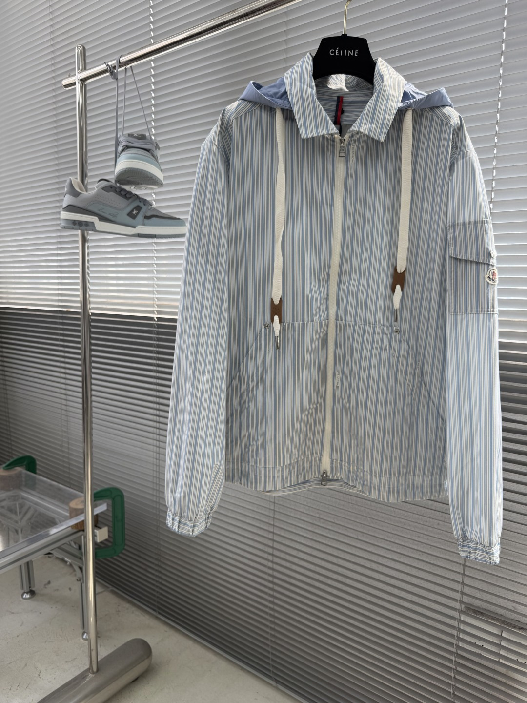 NO:955107,-mon striped shirt-style jacket is made of pure cotton fabric. The fabric has been treated with dual processes of pre-shrinking and soft shaping to avoid the shortcomings of ordinary cotton that is stiff, easy to shrink, and easy to wrinkle. The cotton fiber is fine and tight, soft and moist to the touch, close to the skin without irritation, and has excellent breathability. At the same time, it has a natural and stiff drape, which can perfectly support the loose and neat silhouette of the entire garment. The upper body is not soft or close-fitting, and can easily modify the body shape.  The detachable hood and hood lining are made of nylon fabric. The nylon material is thin and lightweight, has a smooth and flexible texture, and has almost no weight. It has good wrinkle resistance and quick-drying properties, and is not prone to hard wrinkles after being rubbed.  The stripe texture is created using high-end digital printing technology. The ink directly penetrates into the cotton fiber and does not float on the surface of the fabric. The printing color saturation is even, the stripe lines are straight and regular, and the edges of the texture are clear and neat, with no fuzzy edges or misaligned color problems. The overall geometric stripe texture is high-end and simple, and it is extremely fast. The ink does not block the breathable pores of the cotton material, fully retaining the original breathable and soft characteristics of pure cotton, taking into account both beauty and comfort. Details  1. The front adopts high-quality customized zipper opening and closing. The zipper teeth are neatly arranged and the zipper teeth are arranged neatly and tightly. The zipper pulls back and forth smoothly and silently without jamming or falling out of teeth. The placket adopts double-layer reinforced stitching technology, and the wiring is neat and dense. It is not easy to deform or open after long-term opening and closing, which greatly improves the service life of the garment.  2. The front body is equipped with a large kangaroo-style pocket. The bag body has sufficient capacity. The bag mouth is reinforced with a seam, which is strong in load-bearing and not easy to deform. The sleeves have exclusive custom-made snap-button pockets. The metal snap-buttons open and close crisply and tightly, and are tightly closed and not easy to loosen. They are both decorative and practical.  3. The hem is equipped with an adjustable drawstring design and an exclusive metal rope buckle. You can freely tighten the hem to create a loose/slim fit, while effectively preventing wind and temperature. The hem is fully hemmed with dense sewing technology, and the corners are smooth and neat without excess threads. Size 1 2 3 4 Sizes Length Bust Shoulder Width 1 68.5 11849 270122 50 3 71.5126 51  473130 52,,jackets & coats,shirts,hats,19860909-mon 条纹衬衫式夹克 衣身通体采用纯棉面料,面料经过预缩、柔软定型双重工艺处理,规避普通棉布生硬、易缩水、易起皱的缺点.棉料纤维细腻紧实,触感柔软温润,贴身穿亲肤无刺激,透气性极佳；同时其自带自然挺括的垂坠感,能够完美撑起整件衣服的宽松利落廓形,上身不软塌、不贴身,轻松修饰身形. 可拆卸兜帽及兜帽里料均采用锦纶面料,锦纶材质轻薄轻量化,质地顺滑柔韧,几乎无自重,其自带良好的抗皱性与速干特性,揉搓后不易产生硬褶. 条纹纹理采用高端数码印花工艺打造,墨水直接渗透棉纤维内部,并非浮于面料表面.印花色彩饱和度均匀、条纹线条笔直规整,纹路边缘清晰利落,无模糊毛边、无错位晕色问题,整体几何条纹质感高级简约、牢度极强,墨水不堵塞棉料透气孔隙,完全保留纯棉原本的透气、柔软特性,美观度与舒适度兼顾. 细节 1、正面采用高品质定制拉链开合,拉链齿排列整齐紧密,来回拉动顺滑静音、不卡顿、不脱齿.门襟采用双层加固车线工艺,走线工整密实,长期开合使用不易变形、开线,大幅提升成衣使用寿命. 2、前身配置袋鼠式大口袋,袋体容量充足,袋口加固锁边,承重性强、不易变形.衣袖专属定制按扣口袋,金属按扣开合清脆紧实,闭合严密不易松脱,兼具装饰性与实用性. 3、衣摆搭载可调节抽绳设计,搭配专属金属绳扣,可自由收紧下摆、塑造宽松/修身两种版型,同时有效防风锁温.下摆整圈包边密车工艺,边角平整利落,无多余线头. 码数1 2 3 4 尺码衣长胸围肩宽 1 68.5 11849 270122 50 3 71.5126 51 473130 52,,jackets & coats,shirts,hats,,Men's clothing