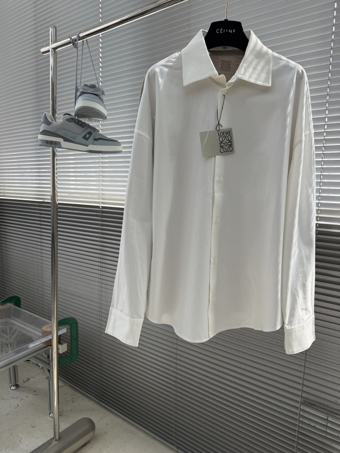 NO:955141,-LOEW cotton and knitted spliced shirt. The front panel is made of high-count cotton yarn through a weaving process with high warp density and low weft density. It is made into a light and extremely breathable fabric. The surface is smooth and flat, and feels as smooth as silk. It also retains the natural skin-friendly properties of cotton, making it comfortable and comfortable against the body without any strange feeling. Because the warp yarns are closely arranged, the surface of the fabric shows a longitudinal texture and soft luster, which enhances the visual sense of luxury.  The back panel is woven with extremely fine wool yarns through high-count spinning technology to make a moderately dense fabric that is soft to the skin and has a fine velvet feel on the surface. The wool fiber has a natural hollow structure, which can lock in still air and form an excellent thermal insulation layer. Even if it is light and thin, it has a good thermal insulation effect.  Under the back collar, the high-precision calculation system of the computerized embroidery machine controls the coordinated operation of the machine head, needle bar, and thread spool. The fabric frame moves accurately in the horizontal and vertical directions to form a stitch track. The upper and lower thread tensions are adjusted to ensure that the stitches are smooth and free of floating threads, forming anagram embroidery with an error of ±0.1mm.  The ironer turns the collar up, irons it from the bottom to the top with high-temperature and moist steam, applies pressure to smooth out the wrinkles, and then turns it over to the front and repeats the operation. Turn to the collar to iron out an arc, and press the back collar to the bottom to keep it stiff. The rotator sleeves are suspended to avoid crushing the edges. After adjusting the fiber density through the ironer's 'push, return, and pull' technology, the shirt can better fit the body curve. Size: 36384042 Size, length, bust, shoulder width  366411661 3865120 62 4066124 63 4267128 64,,loewe,shirts,19860909-LOEW 棉质和针织拼接衬衫 前片选用高支棉纱通过经密高,纬密低的织造工艺制成轻薄且具有极佳透气性的面料.表面光滑平整,触感如丝绸般柔滑,同时保留棉的天然亲肤性,贴身舒适无异样感.因经纱紧密排列,织物表面呈现纵向纹理与柔和光泽,强化视觉高级感. 后幅通过高支纺纱技术,用极细的羊毛纱线织成密度适中的面料,触感柔软亲肤,表面有细腻的绒感.羊毛纤维特性具有天然的中空结构,能锁住静止空气,形成绝佳的隔热层,即使轻薄,也有良好的保暖效果. 后领下方处通过电脑绣花机高精度的计算系统控制机头、针杆、线轴的协同作业,布料框架在水平和垂直方向精准移动,形成针迹轨迹,调整上线和下线张力,确保线迹平整无浮线,形成误差在±0.1mm的anagram刺绣. 熨烫师将衣领翻立,通过高温湿蒸汽从底部向上端熨烫,施加压力抚平褶皱,再翻至正面重复操作.转至领口烫出弧形,后领压至最底以保持挺括.肩袖部分利用悬空法避免压死边缘.通过熨烫师的“推、归、拔”技术调整纤维密度之后,使衬衫更好的贴合人体曲线. 码数:36384042 尺码衣长胸围肩宽 366411661  3865120 62 4066124 63  4267128 64,,loewe,shirts,,Men's clothing