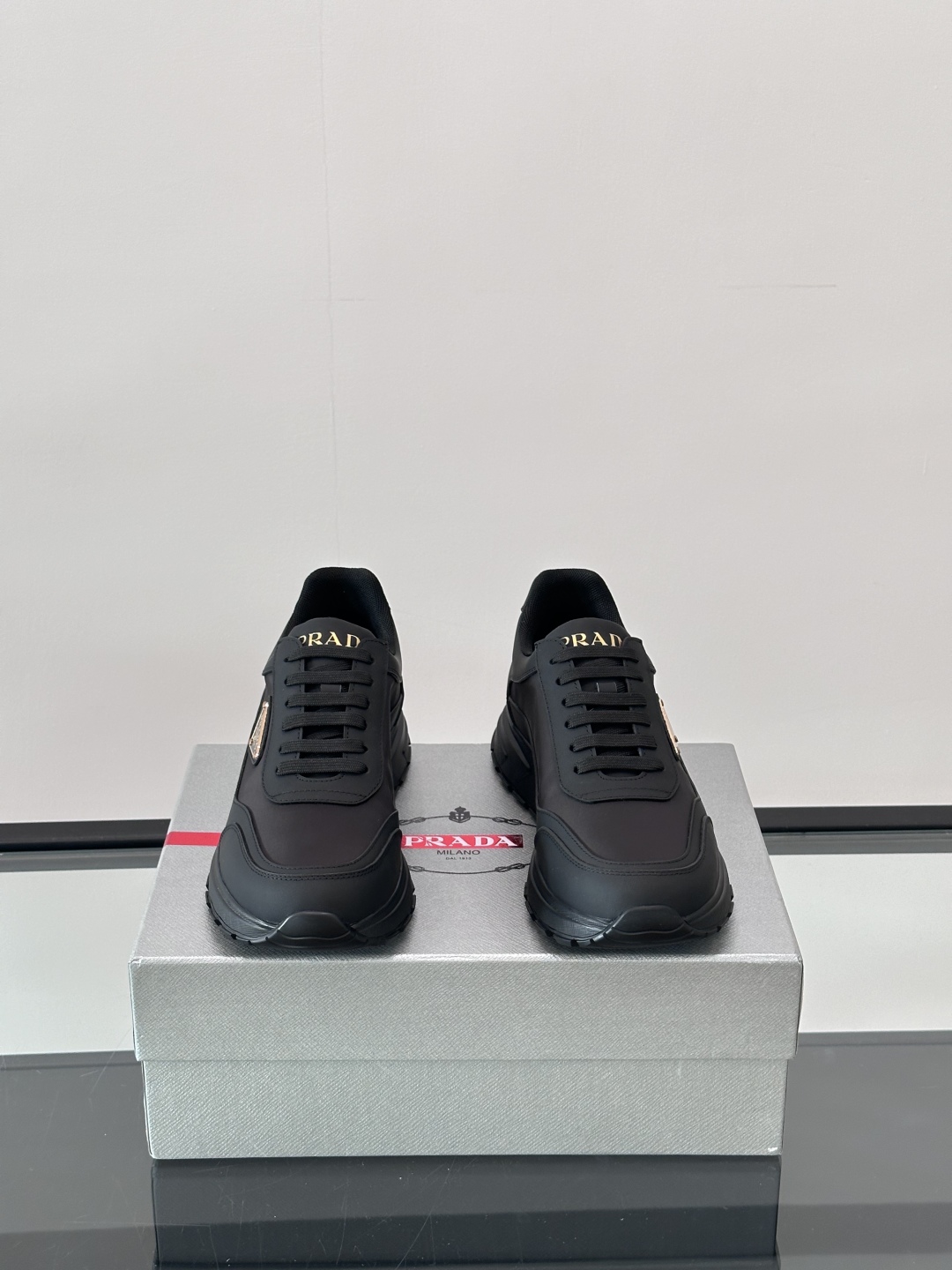 Prada/普拉达 男士新款运动休闲鞋，这款运动鞋鞋面采用进口小牛皮。外侧饰以P家经典金属三角珐琅徽标，