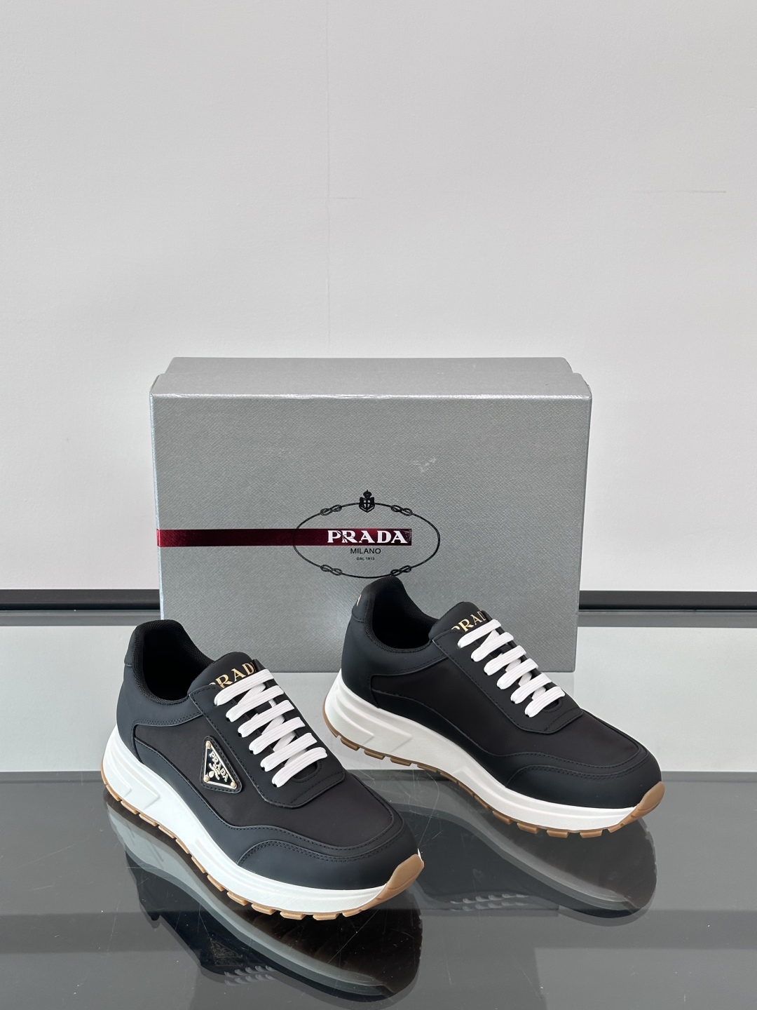 Prada/普拉达 男士新款运动休闲鞋，这款运动鞋鞋面采用进口小牛皮。外侧饰以P家经典金属三角珐琅徽标，