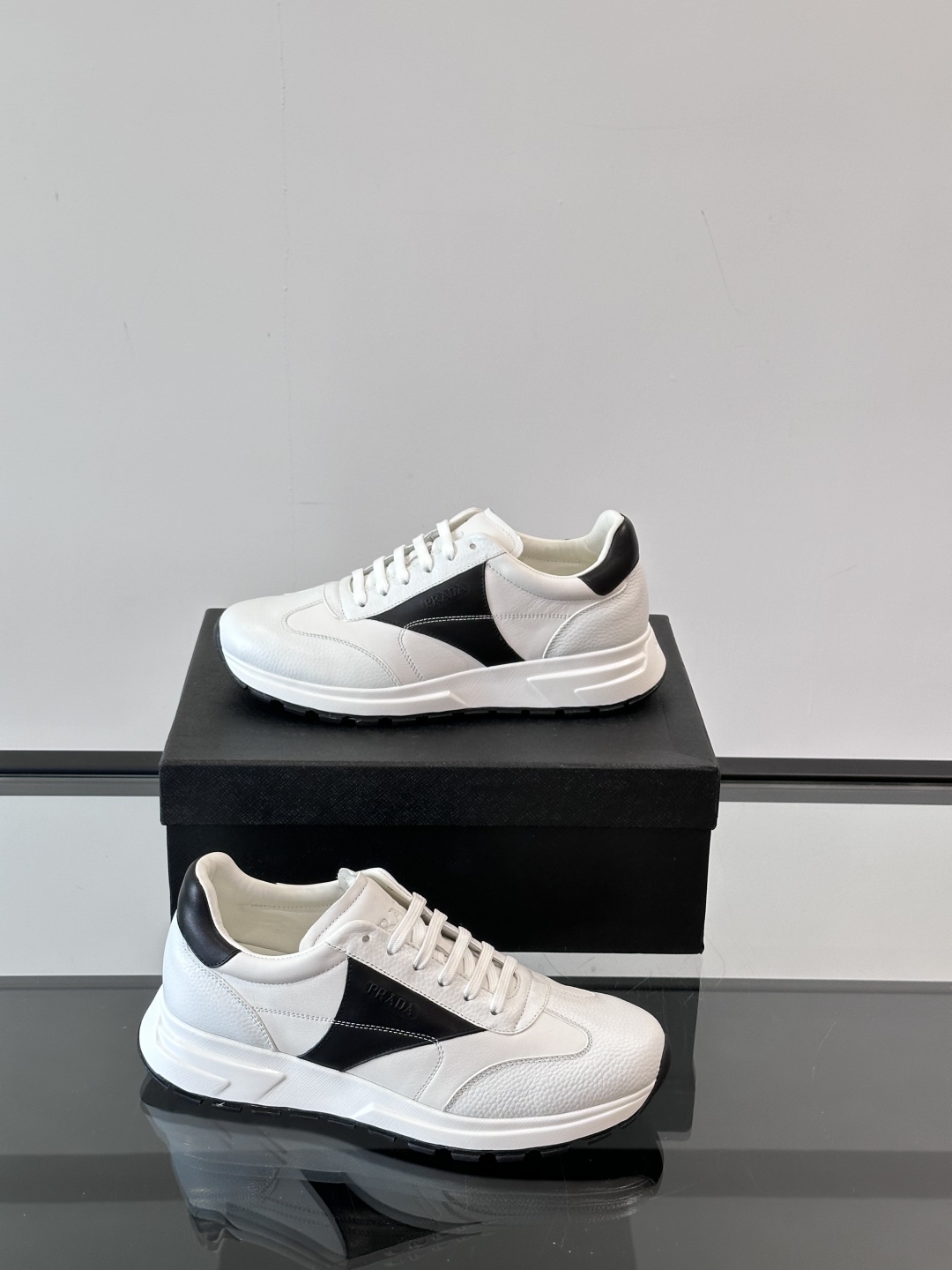 Prada/普拉达 男士新款运动休闲鞋，这款运动鞋鞋面采用进口小牛皮。外侧饰以彩色经典三角图案，真皮内里